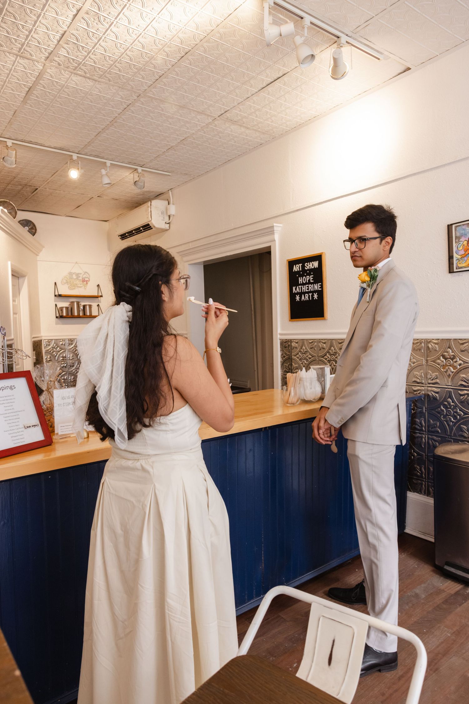 A couple enjoys ice cream together at a vintage-style ice cream parlor counter. Fun elopement photography Rochester NY