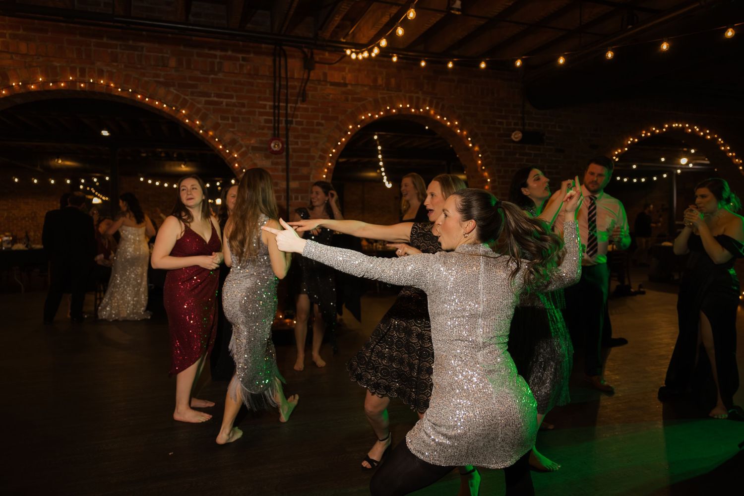 A group of people dancing at a festive outdoor event with string lights and decorations.