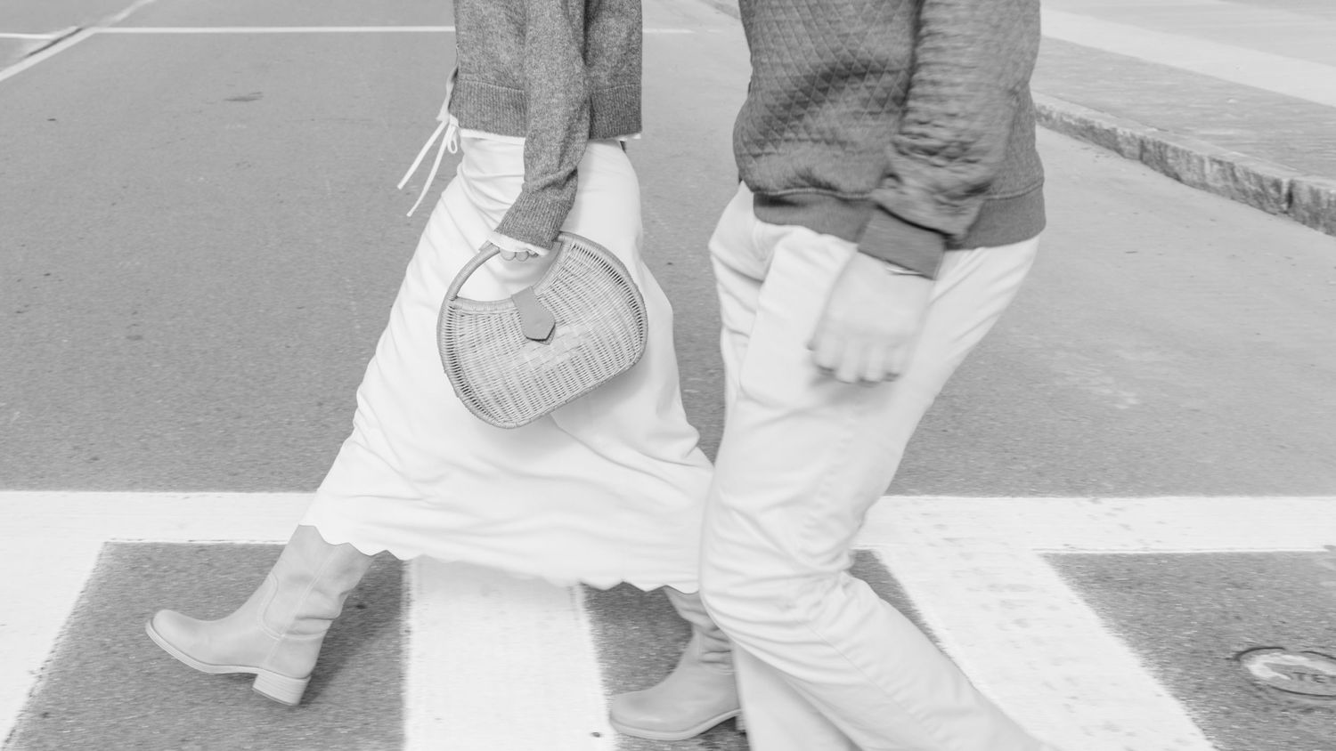 Black and white photo of feet standing close together on a white surface.