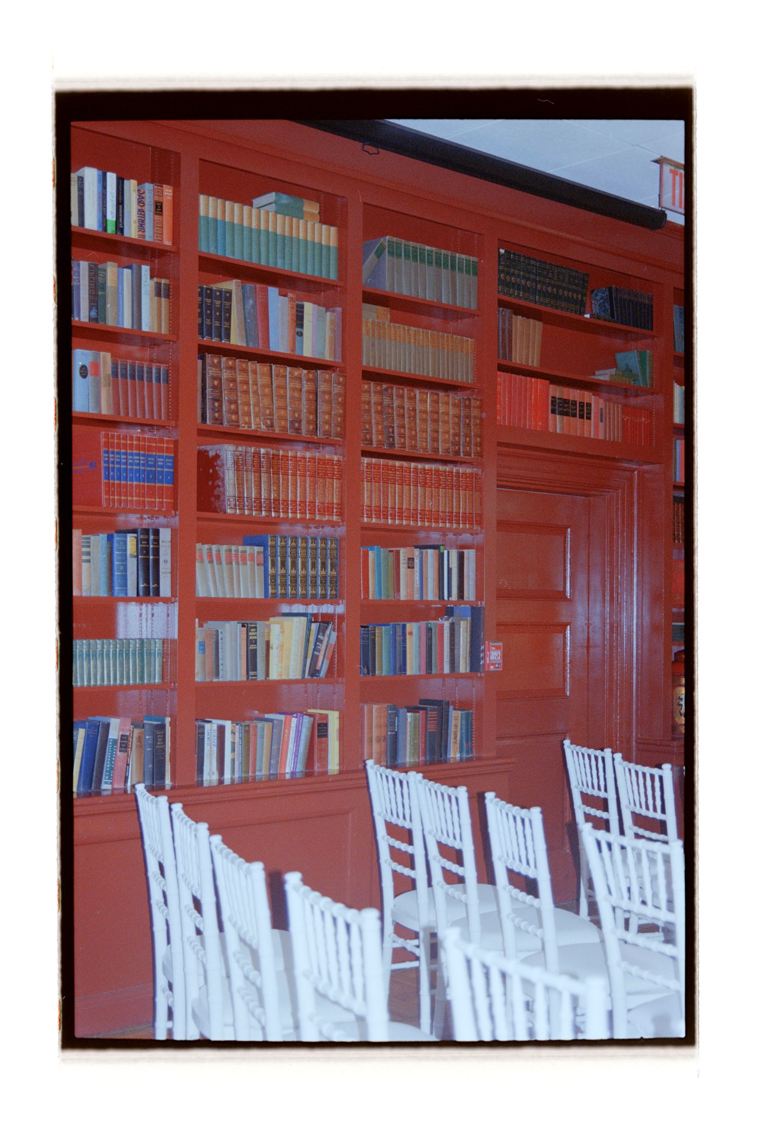 Library room with wooden bookshelves and white chairs arranged in rows. Rochester NY Film wedding photography