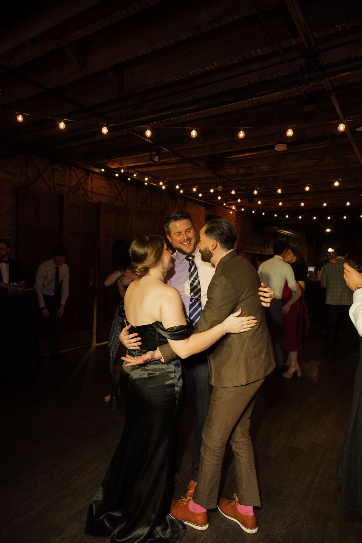 A couple dancing under a string of lights at a social event or celebration.