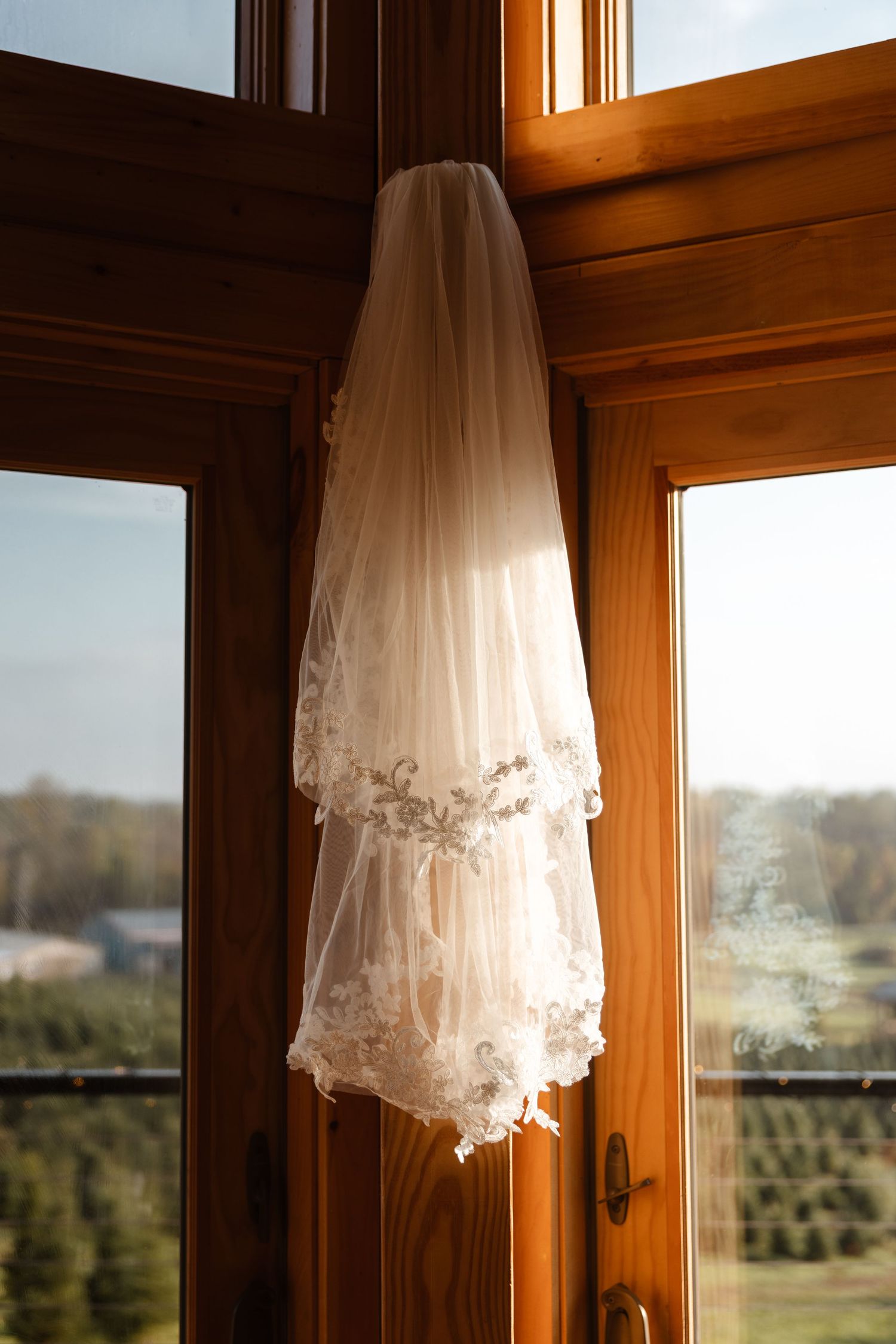 A delicate white wedding veil hangs in front of a sunlit window. wedding photographer Syracuse
