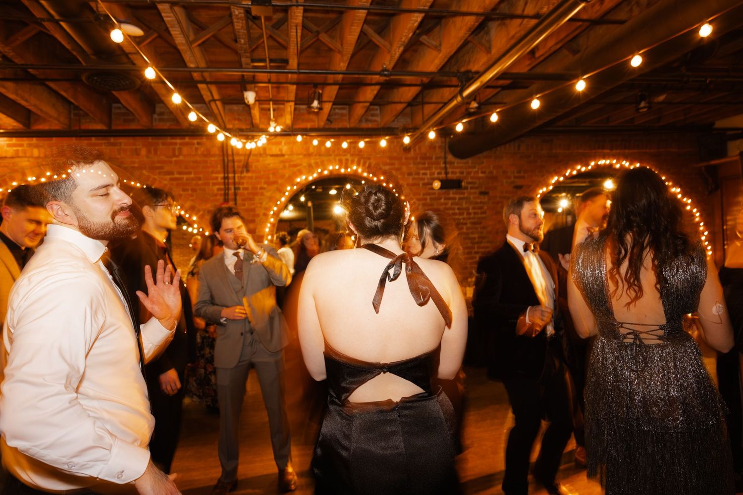 A crowded dance floor with people dancing at a lively wedding reception.