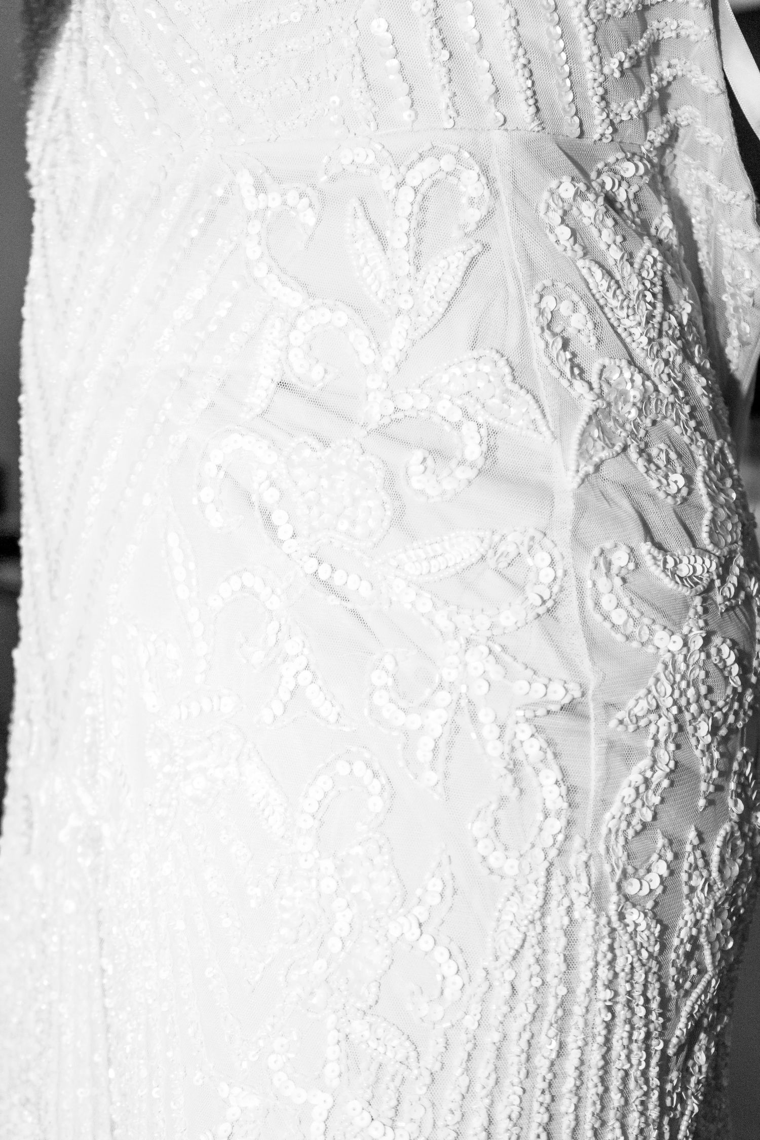 Close-up details of intricate white lace and beadwork on formal attire. Ithaca outdoor wedding photographer