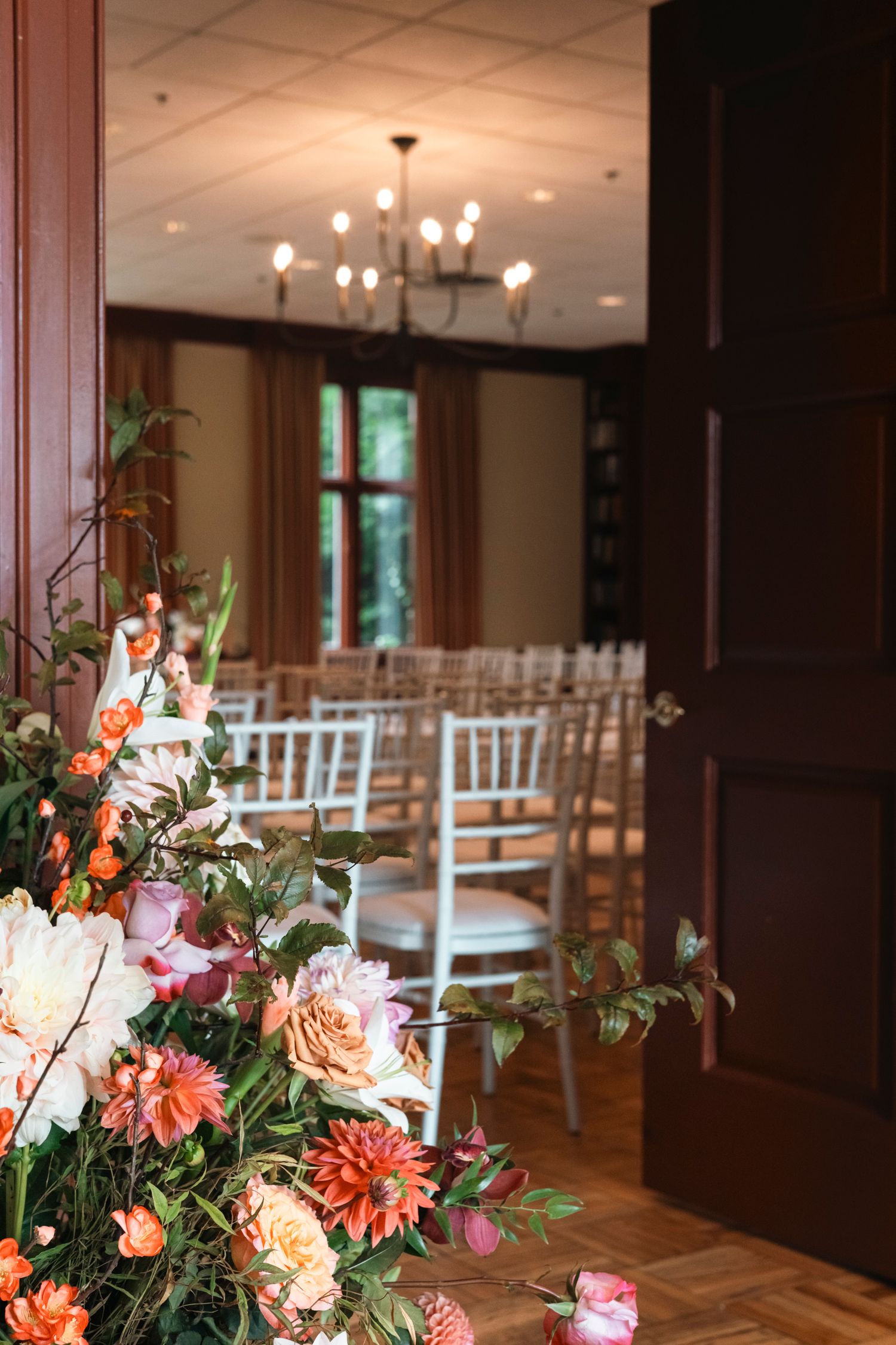 Wedding venue interior with white chiavari chairs and coral floral decorations. Film wedding photographer Rochester  NY