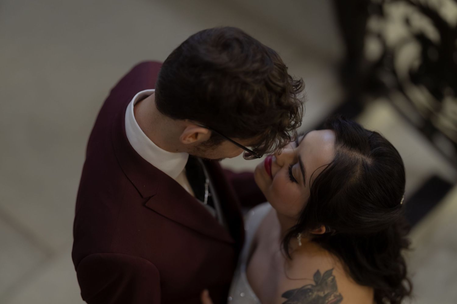 Two people share an intimate kiss at a wedding ceremony in soft lighting.