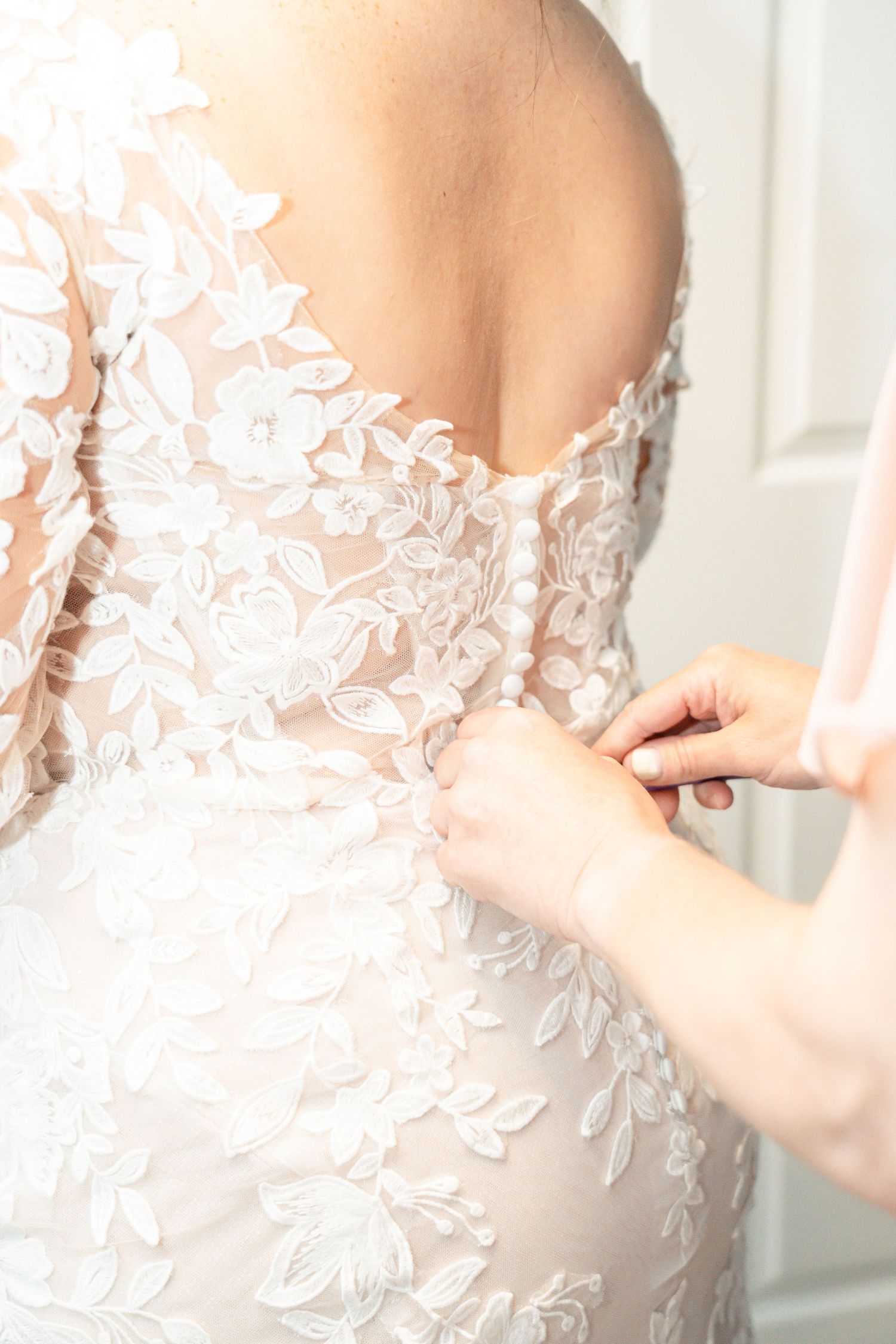 Close-up detail of intricate white lace appliques on a wedding dress bodice.  Camp Brockway Wedding photographer
