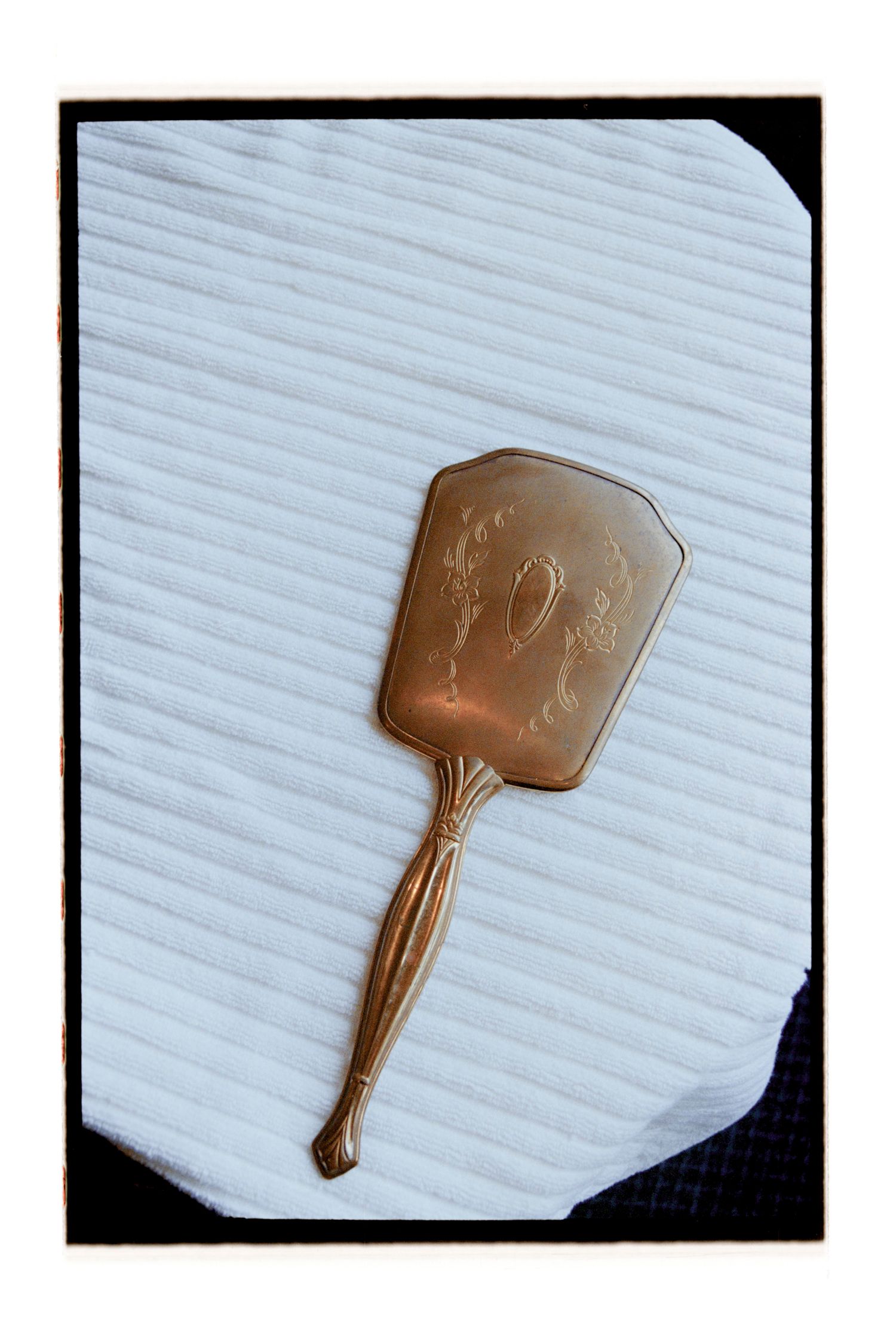 Decorative copper hand fan photographed against white textured background. Rochester NY Film wedding photography