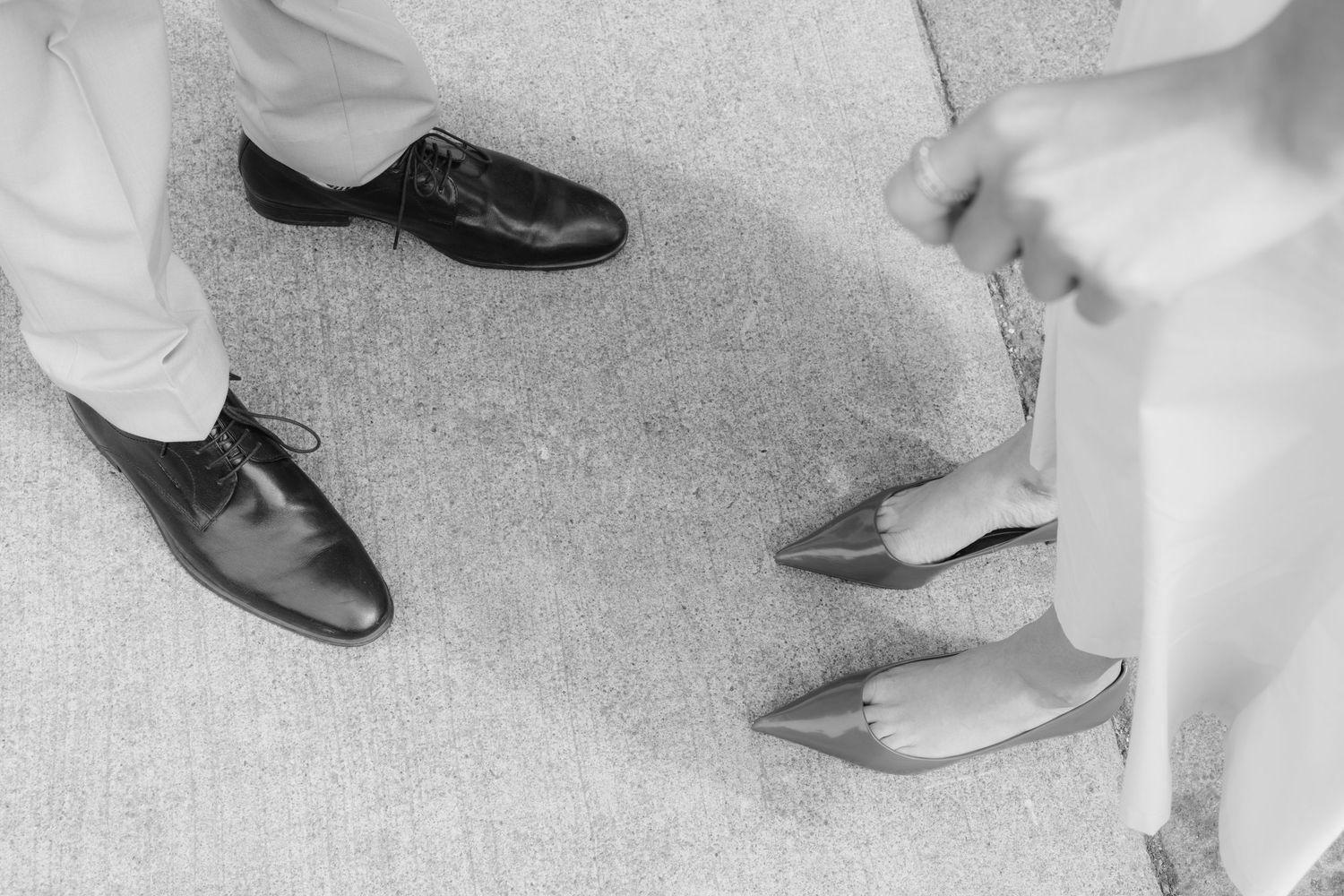 Black and white photo of dress shoes and heels on a carpeted floor. Rochester NY elopement photographer