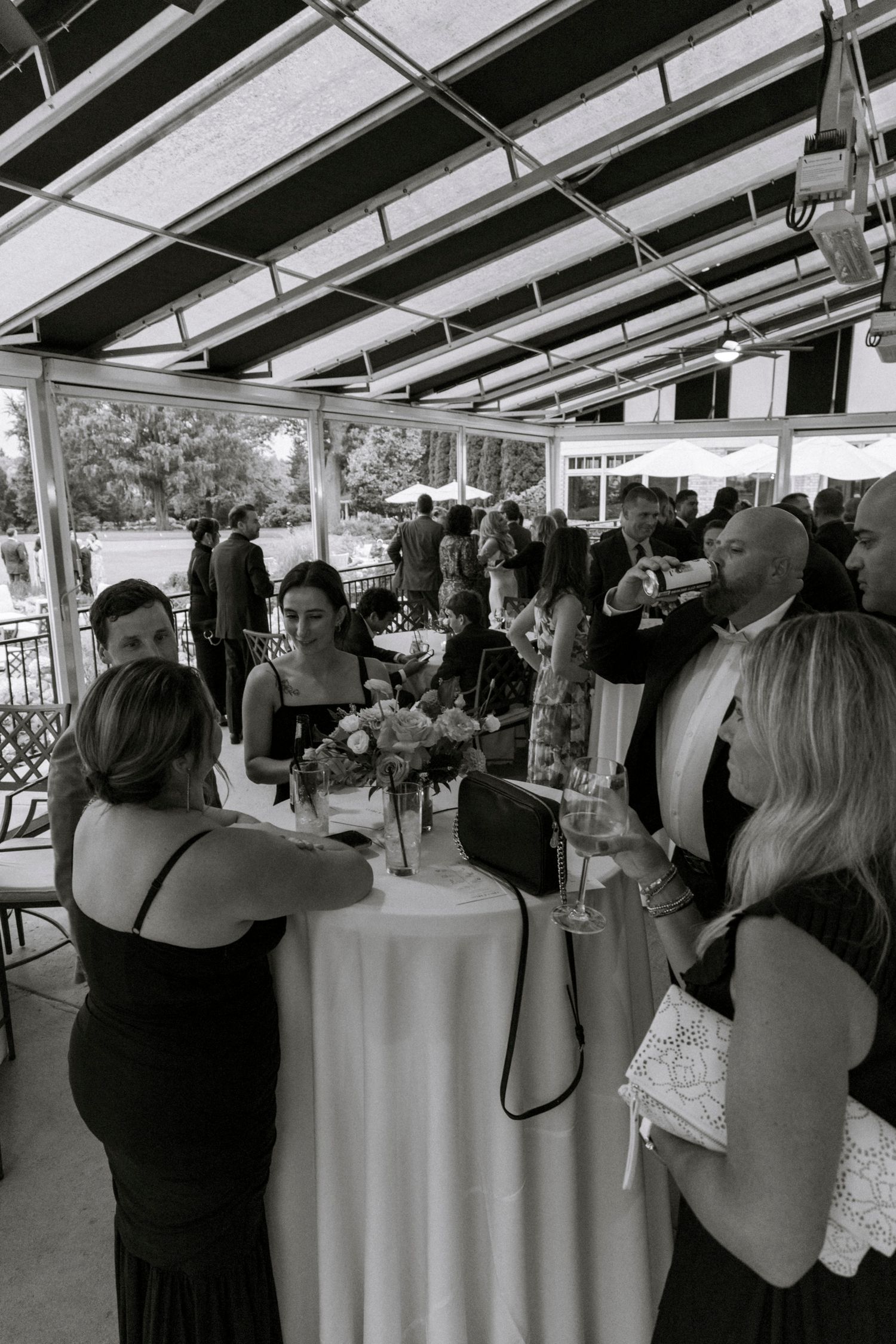 Wedding reception under a covered outdoor venue with guests mingling. Rochester NY documentary wedding photography