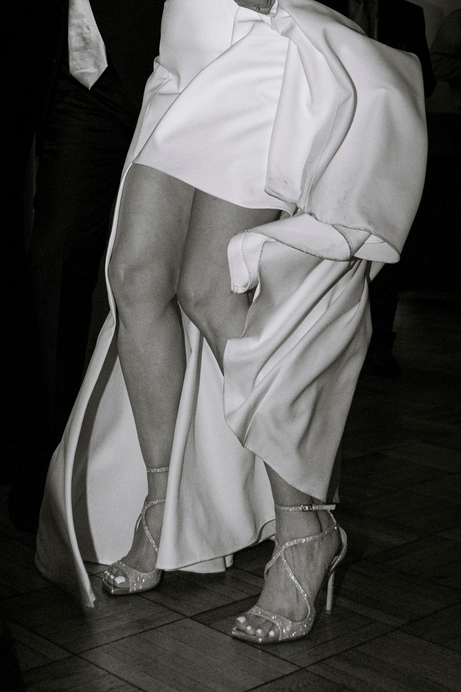 Black and white photo showing feet and hemlines of formal dresses on a dance floor. Rochester NY candid wedding photography