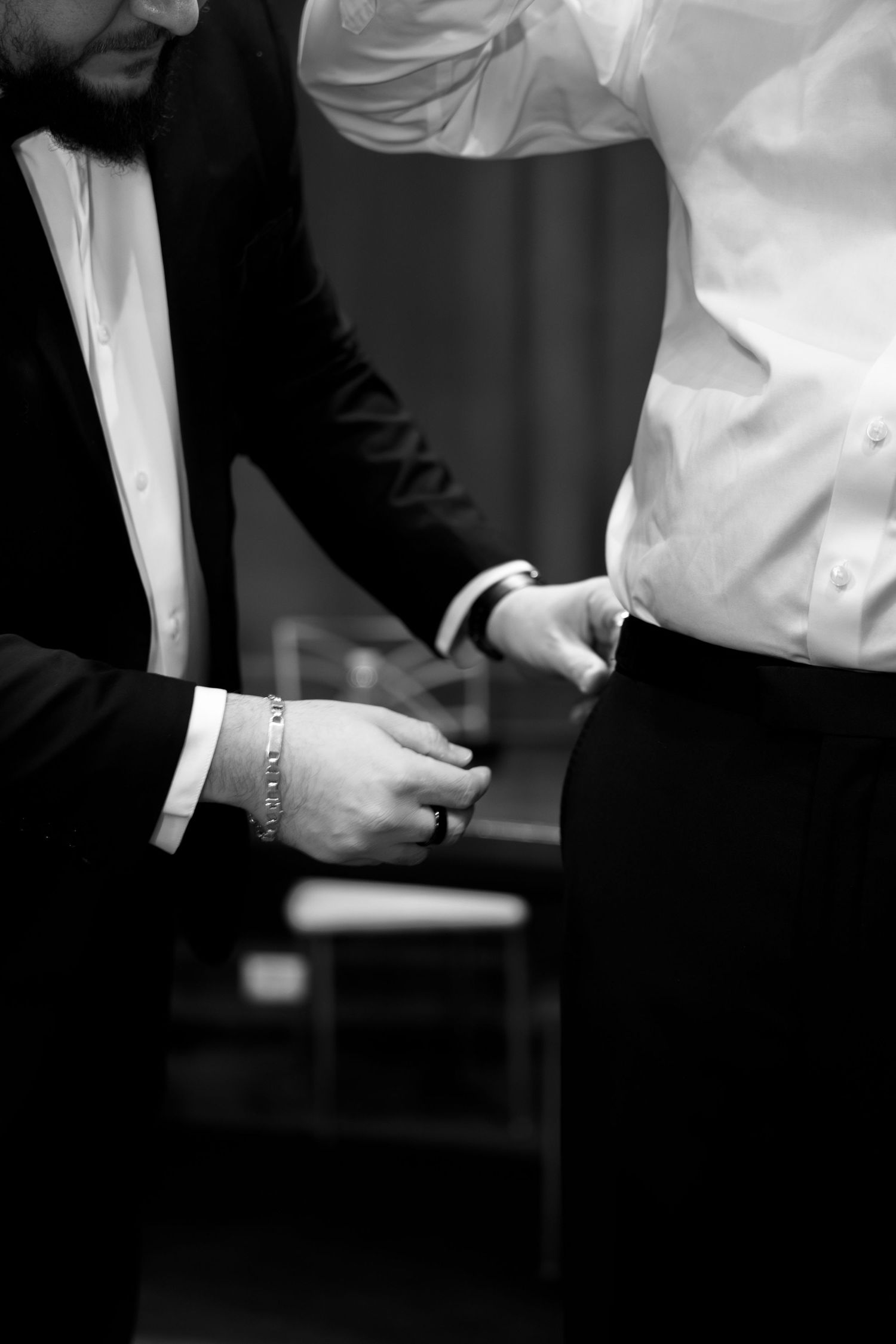 People in formal attire adjusting clothing and accessories.