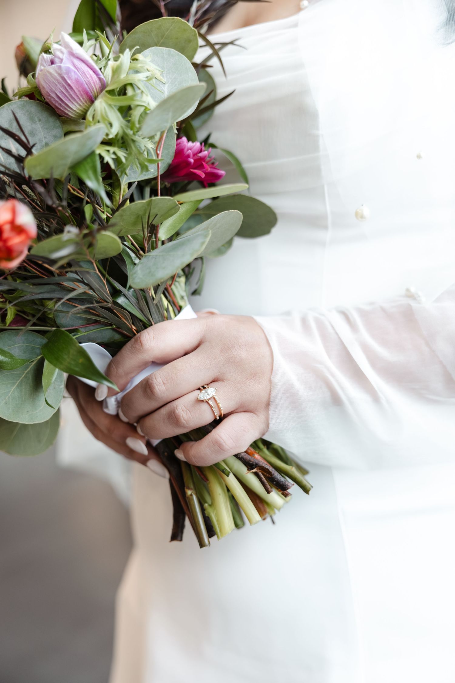 Close-up of hands holding vibrant wedding bouquet with pink flowers and greenery. Arbor Midtown wedding photographer
