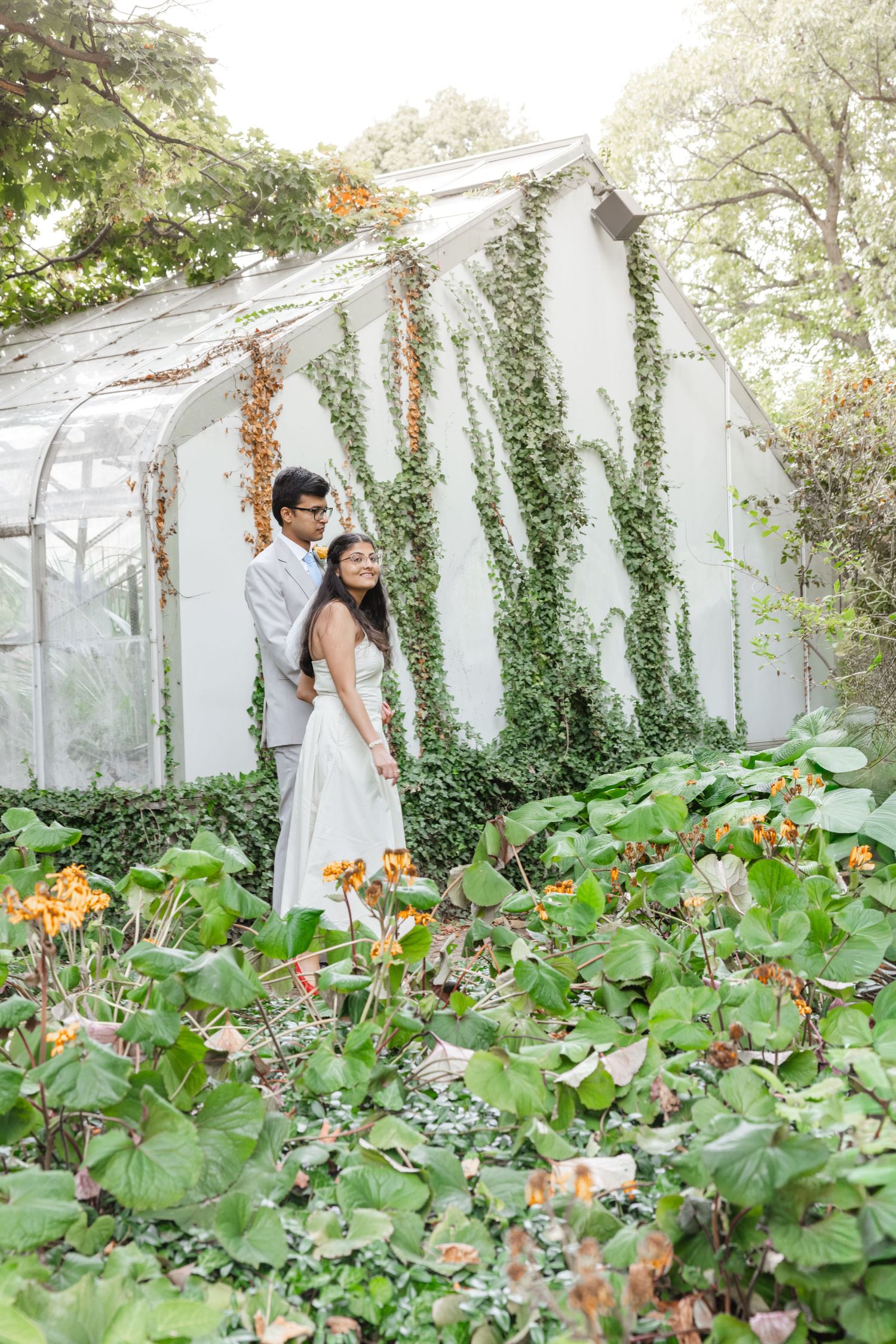 Wedding photography in a greenhouse with ivy and colorful flowers creating a romantic atmosphere.  Rochester conservatory wedding photograph