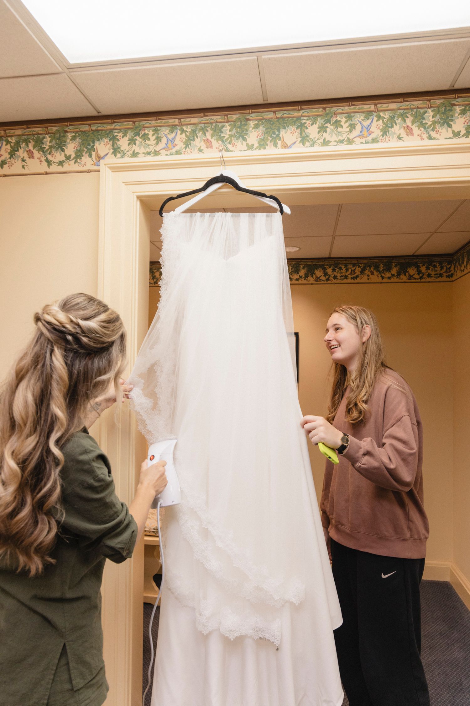 Wedding dress preparation scene with attendants helping to arrange the gown.Rochester NY documentary wedding photography