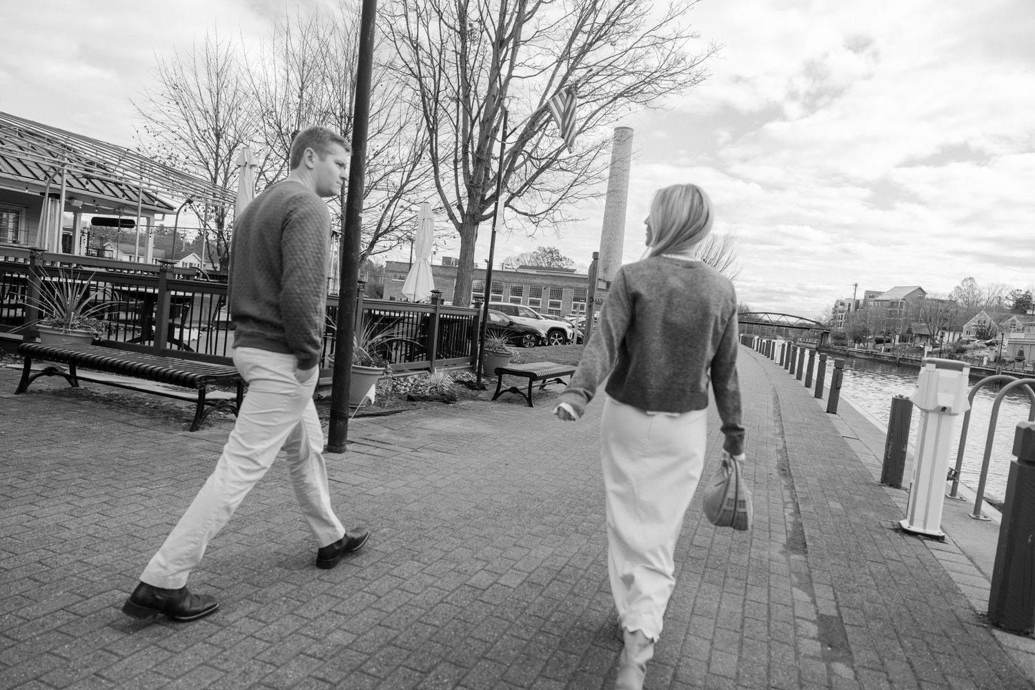 A couple walking along a waterfront promenade in black and white photography. Film wedding photographer Rochester  NY