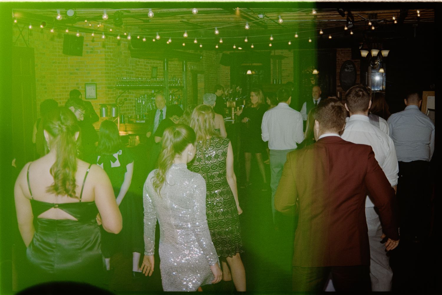 An image of a crowded dance floor with people dancing under green lighting.