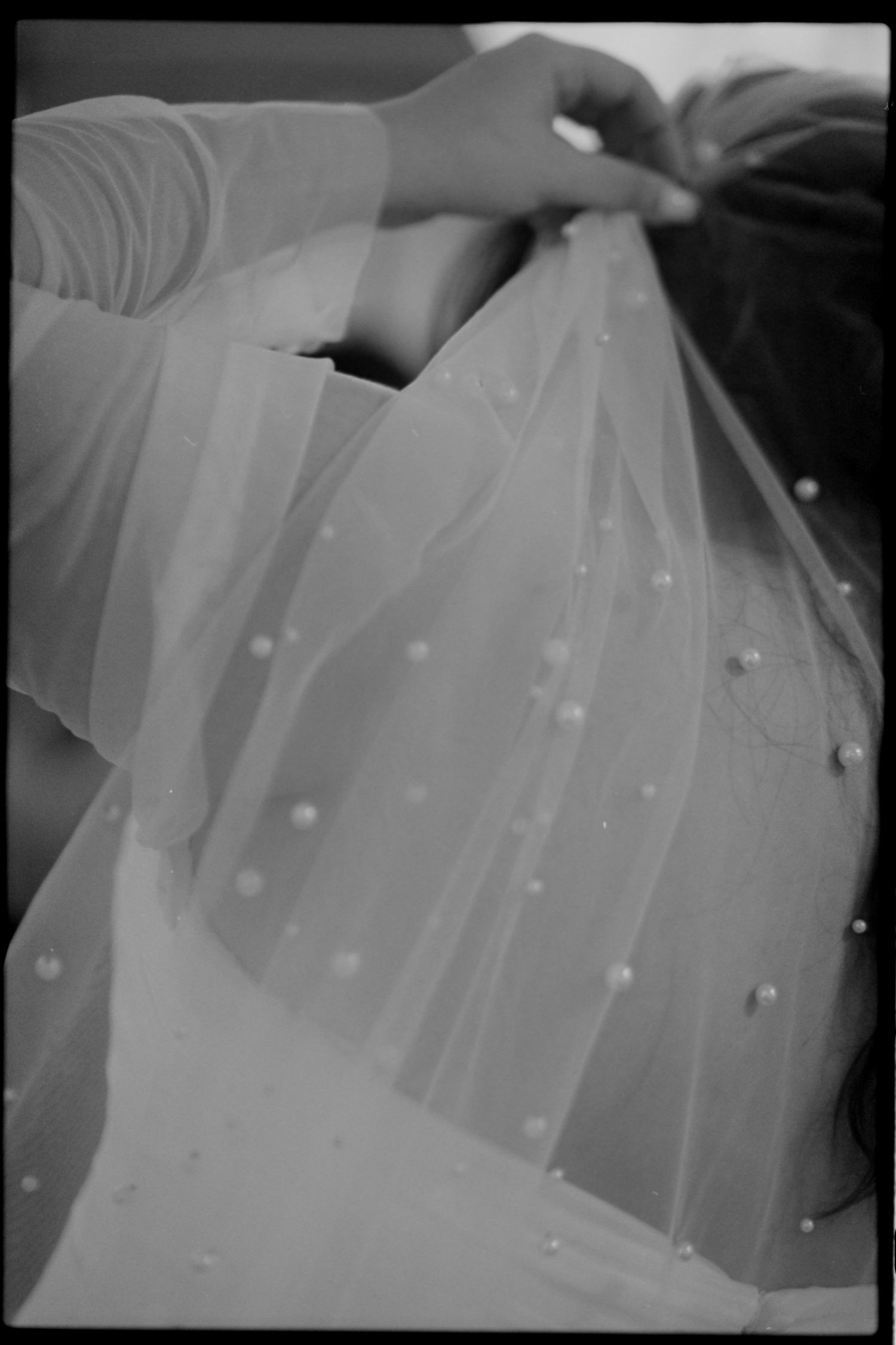 Black and white detail shot of a wedding veil with pearl embellishments.