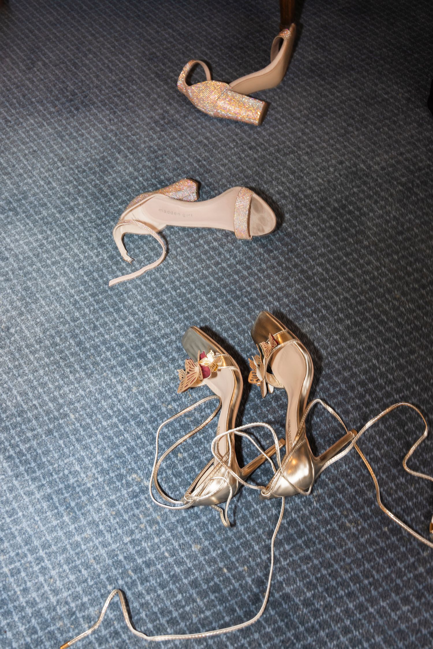 Nude-colored wedding shoes scattered on blue carpeting.Rochester NY documentary wedding photographer