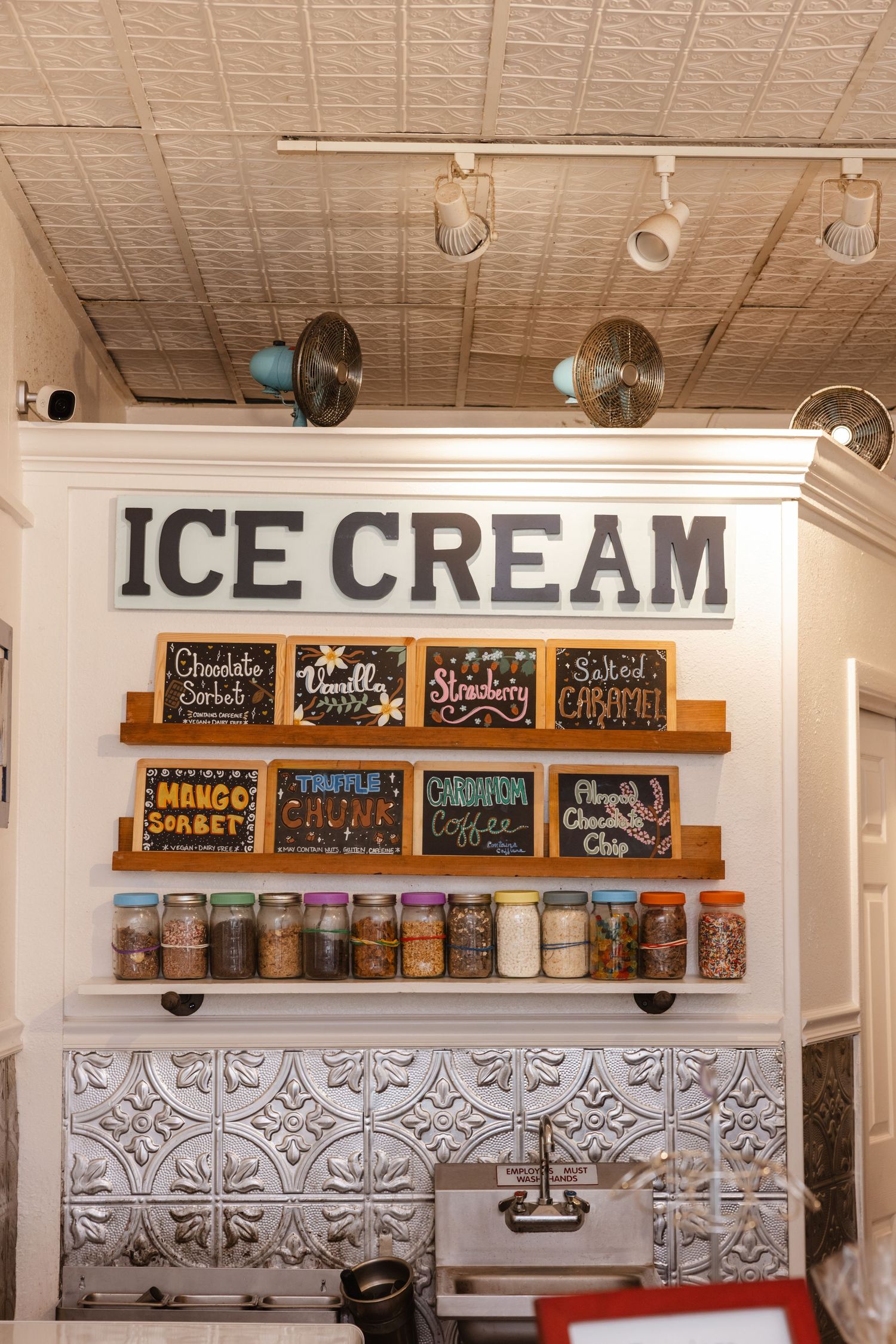 An ice cream shop wall display featuring chalkboard menus and glass storage jars. South wedge elopement