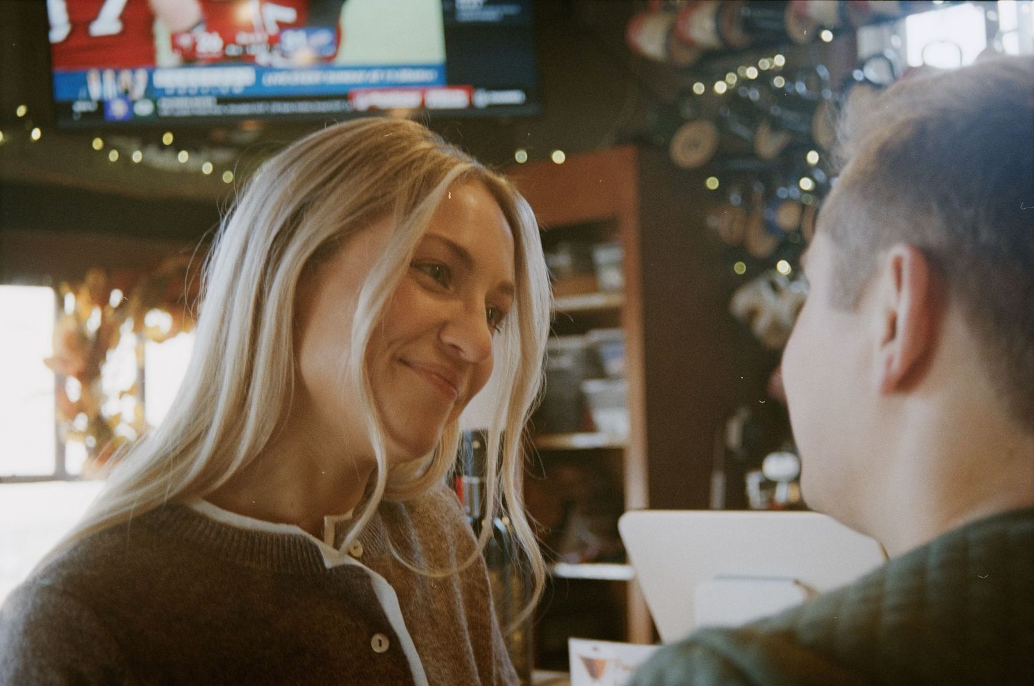 A cozy indoor moment between a couple at a restaurant with warm lighting.