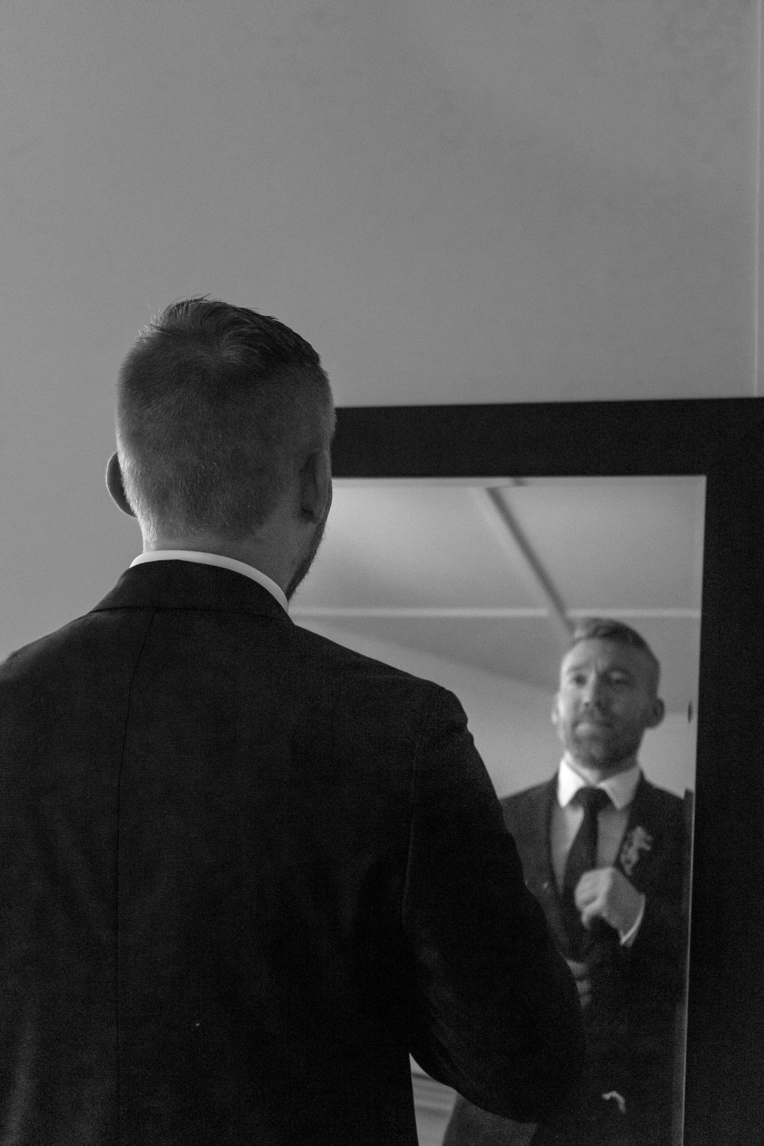 A series of black and white shots showing someone adjusting their tie in a mirror. Ithaca outdoor wedding photographer