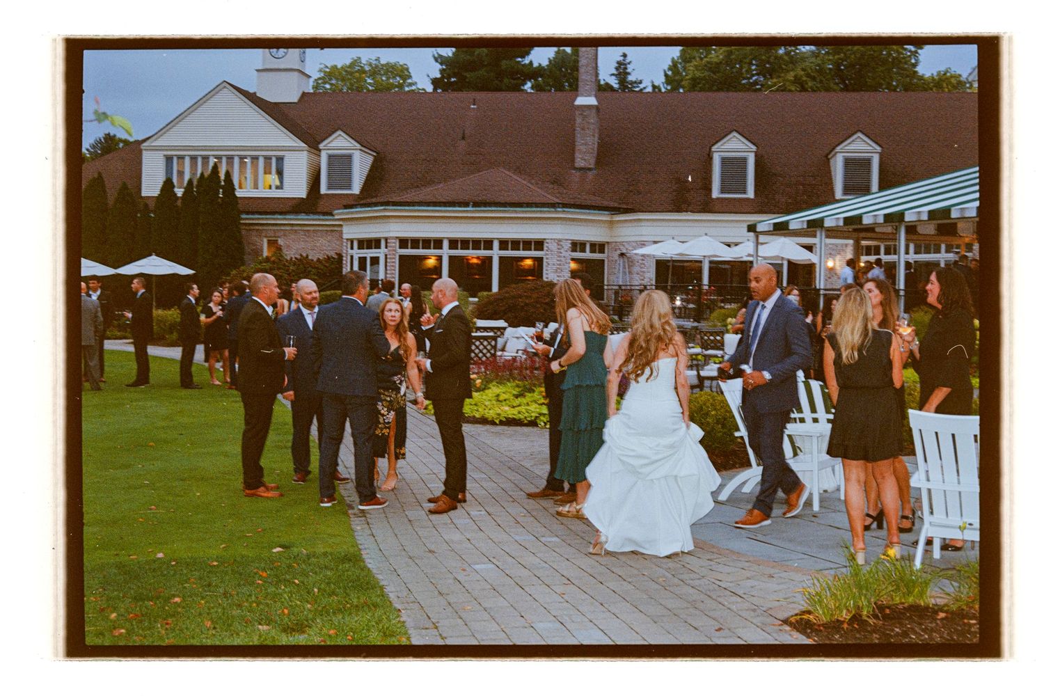 Outdoor wedding ceremony setup with white chairs and guests on a paved patio area. Rochester NY Film wedding photography