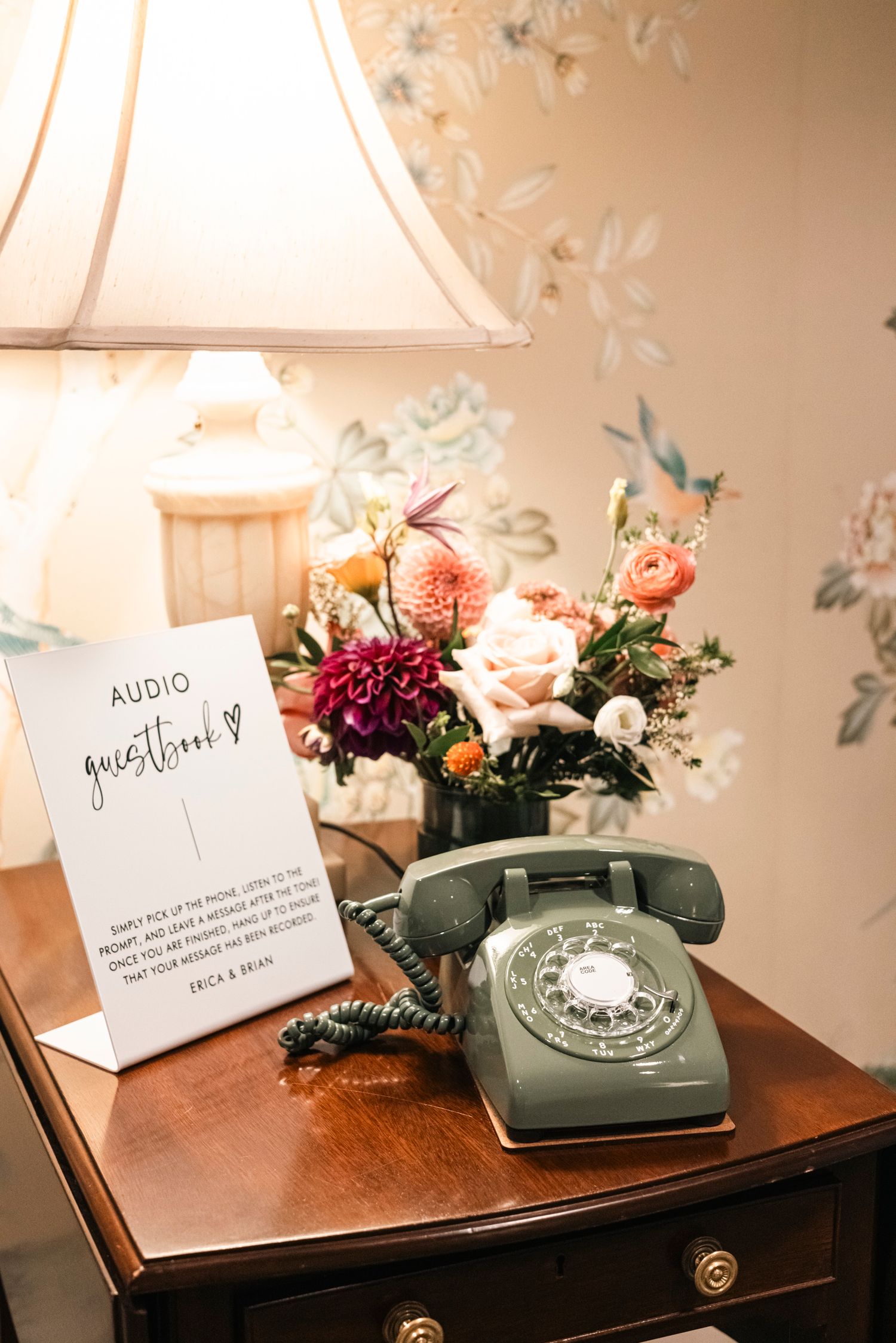 Vintage rotary telephone and floral arrangement on wooden table with guest book sign.Rochester NY documentary wedding photographer