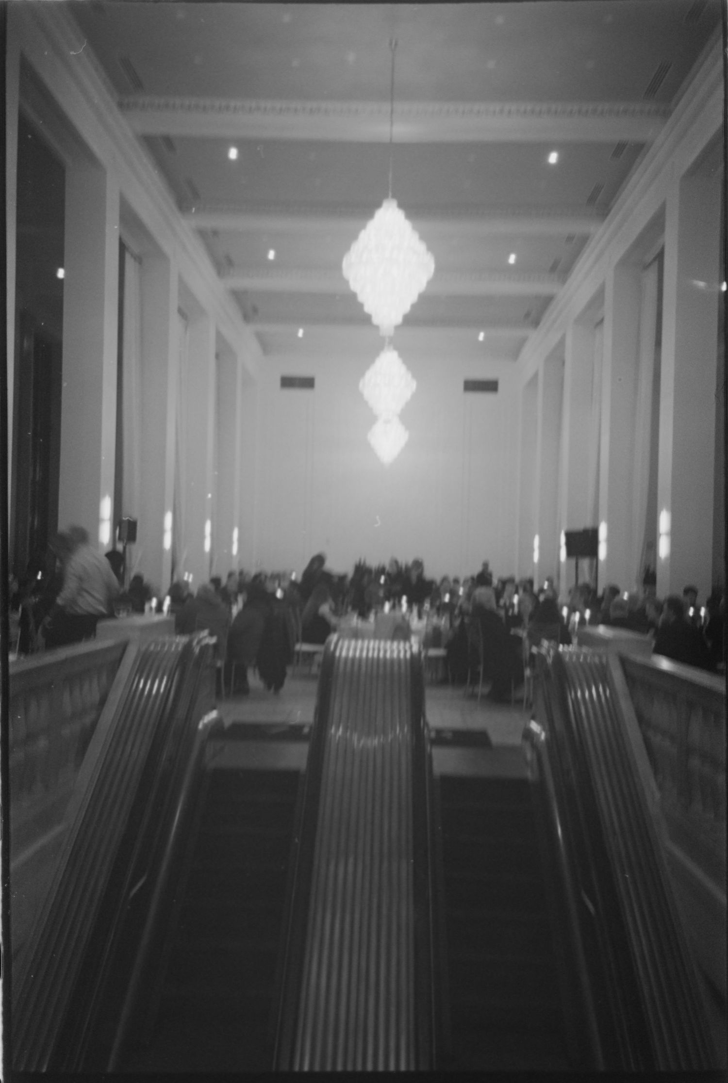 Elegant ballroom with rows of chairs and crystal chandeliers hanging from a coffered ceiling. Rochester NY film wedding photographer