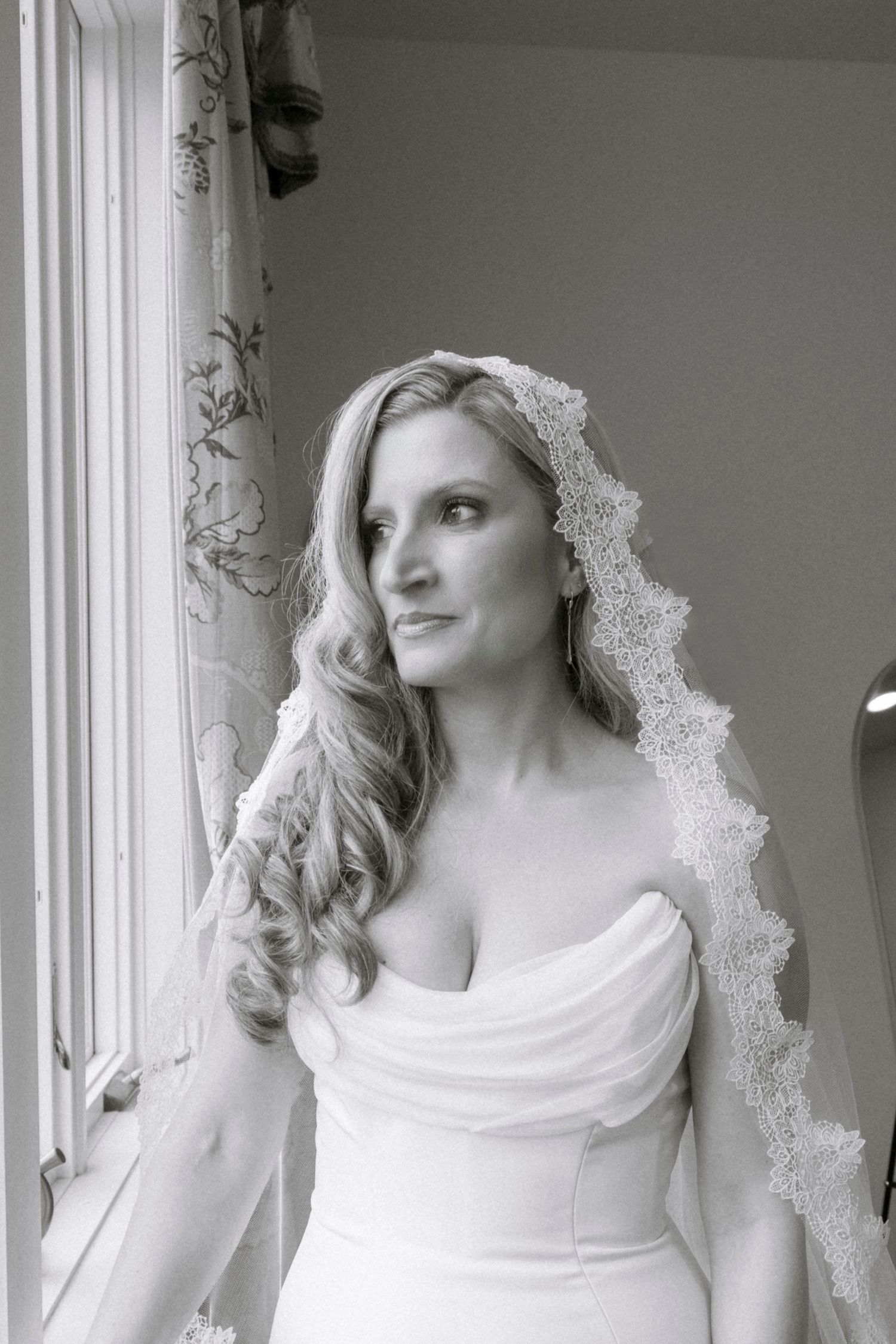 Artistic bridal portrait by a window featuring a lace veil and strapless wedding gown.Rochester NY documentary wedding photography
