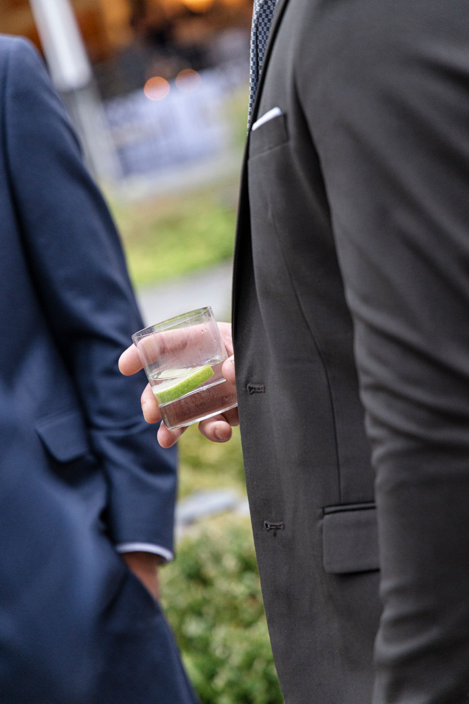 Detail shot of men in dark suits standing in a row at a formal event. Rochester NY documentary wedding photography