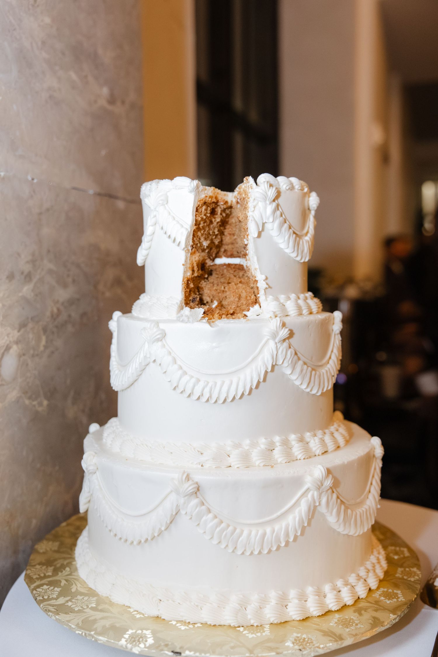 A classic white wedding cake with elegant piping and swag details on a gold base. Arbor Midtown wedding photographer