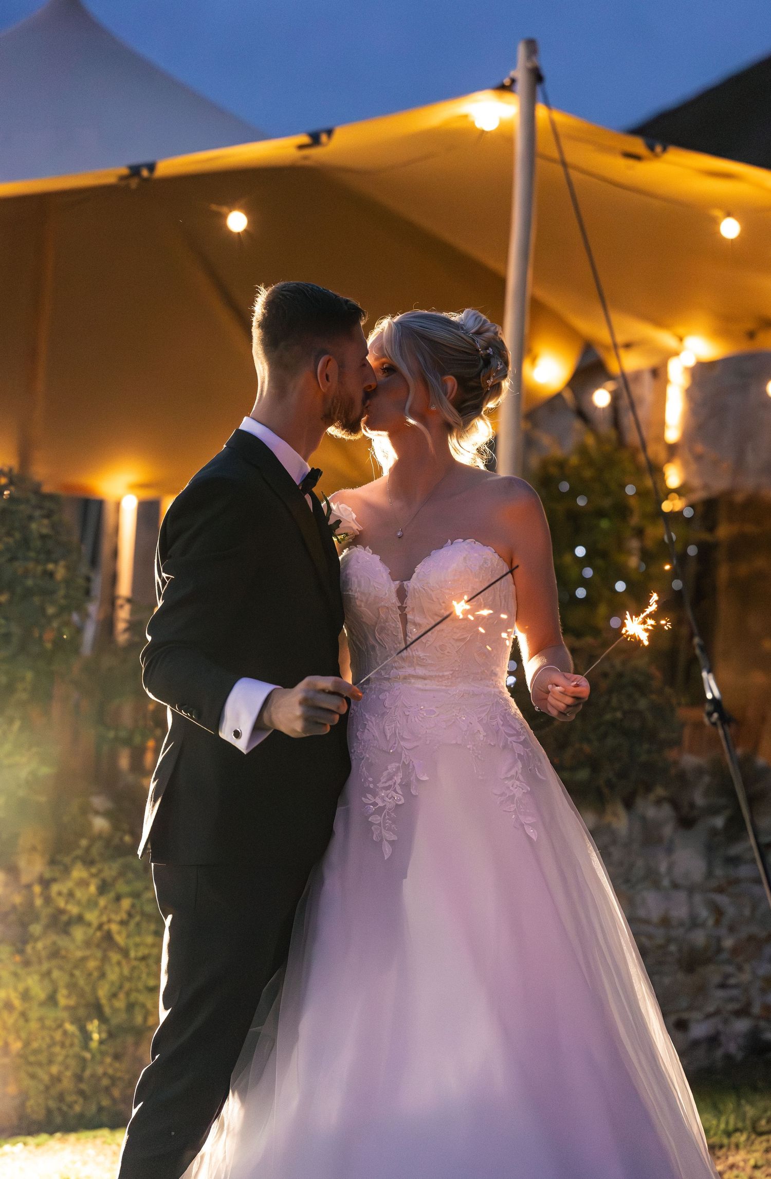 bride and groom holding sparklers and sharing a kiss