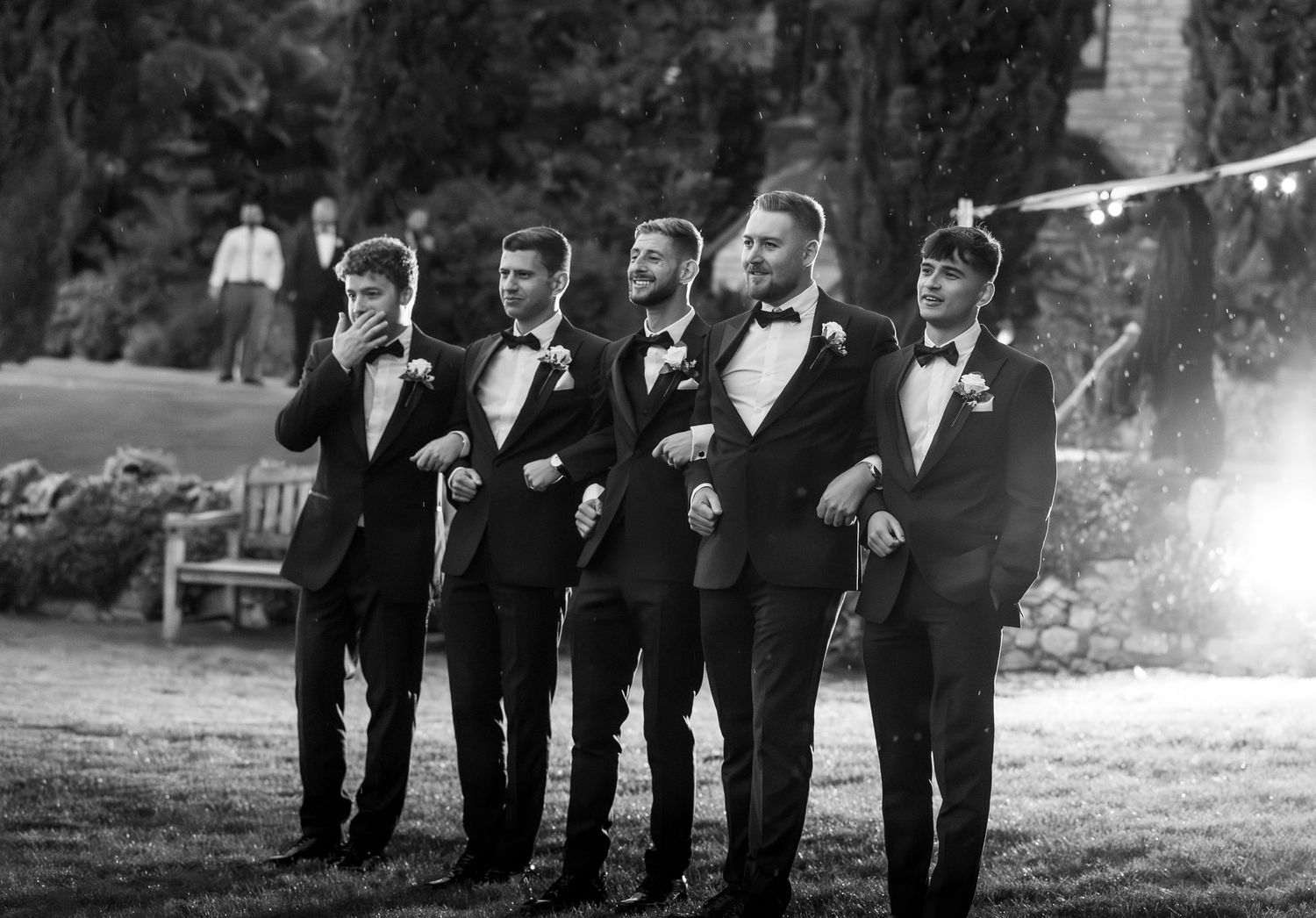 Black and white staged image of groomsmen in a natural environment