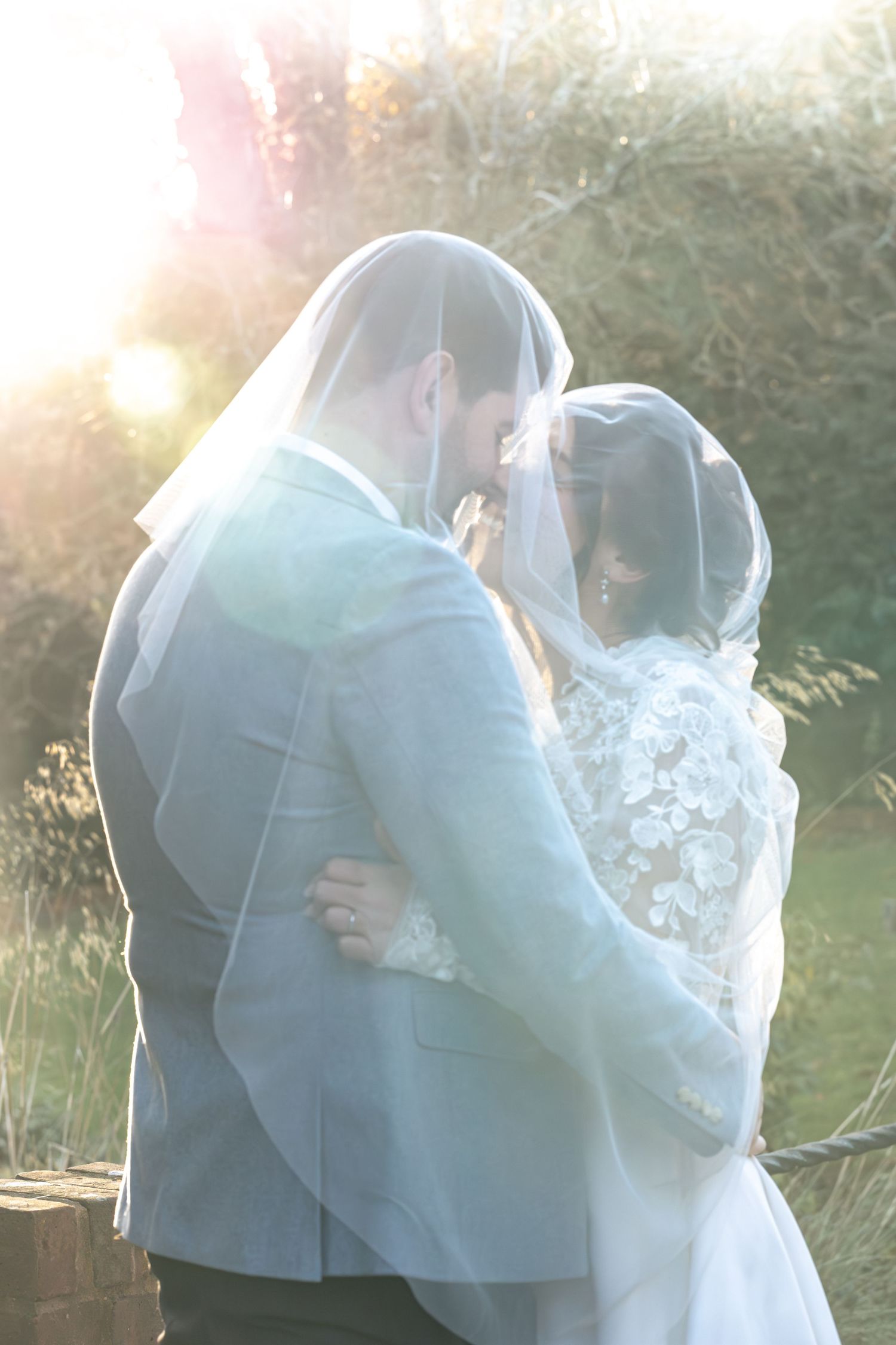 Backlit Image of Bride and Groom under veil