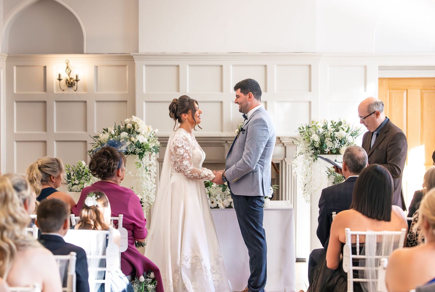 Ceremony image detailing bride and groom holding hands, and guests in the foreground