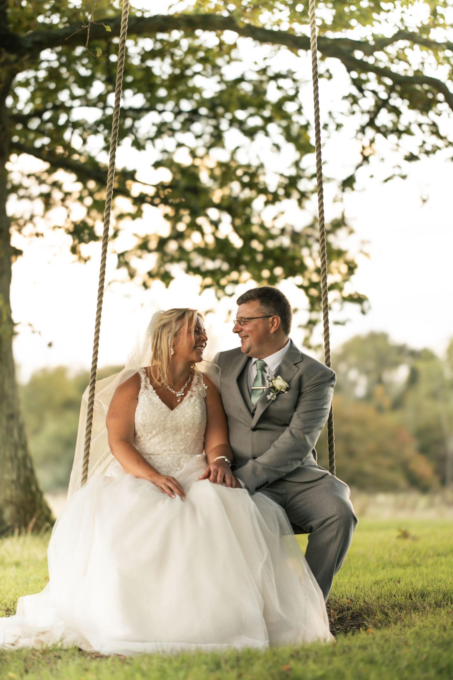 Bride and Groom sat on rope swing in natural environment