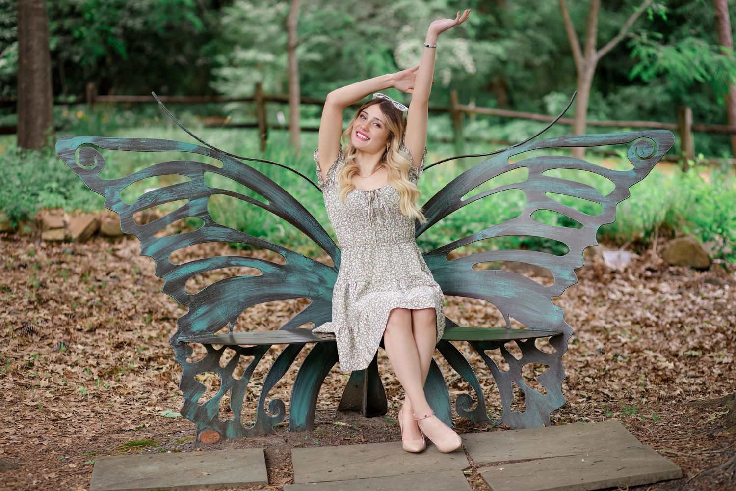 Whimsical portrait on decorative butterfly bench in garden setting.