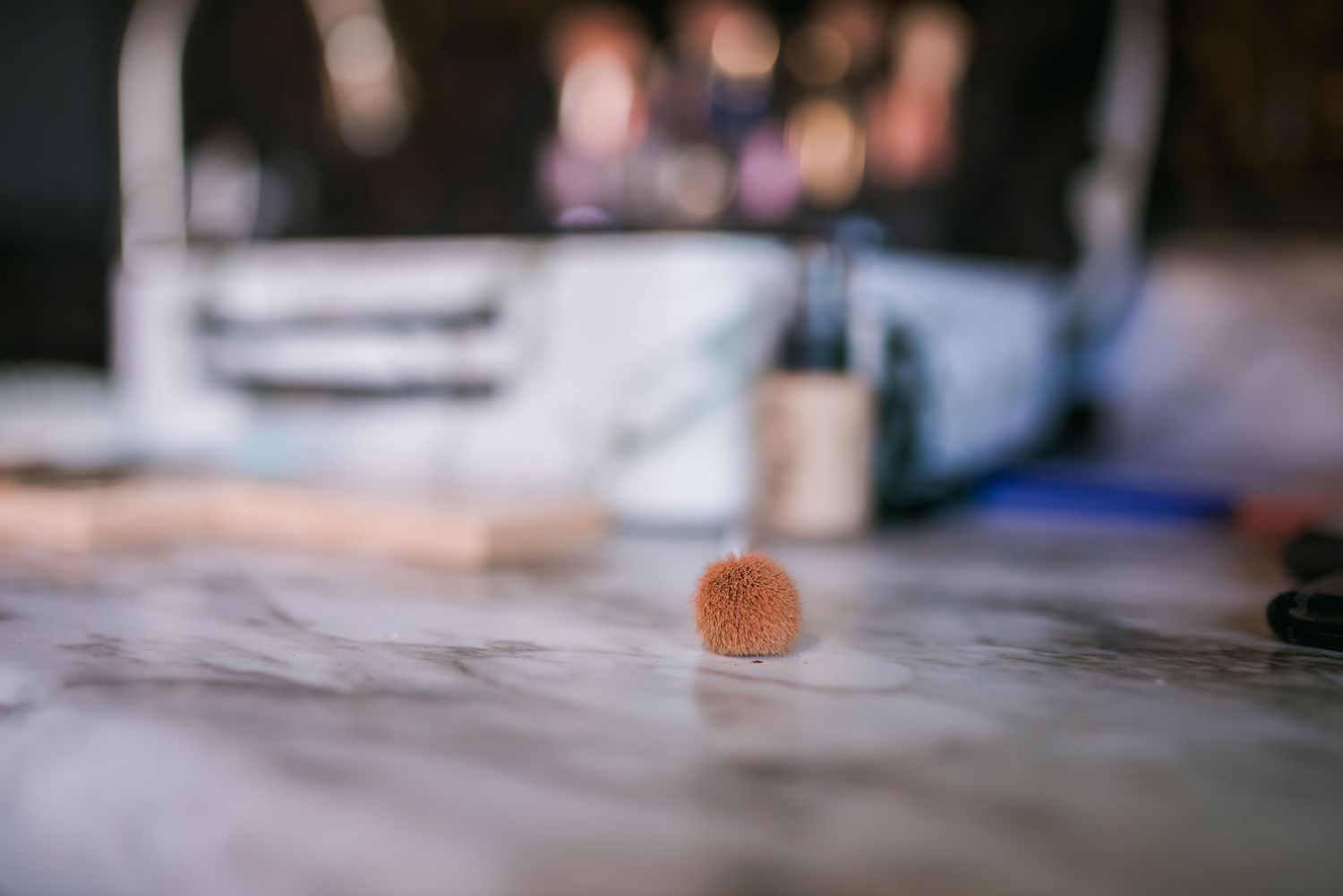 Orange jelly candy sits alone on a blurry marble surface with shallow depth of field.