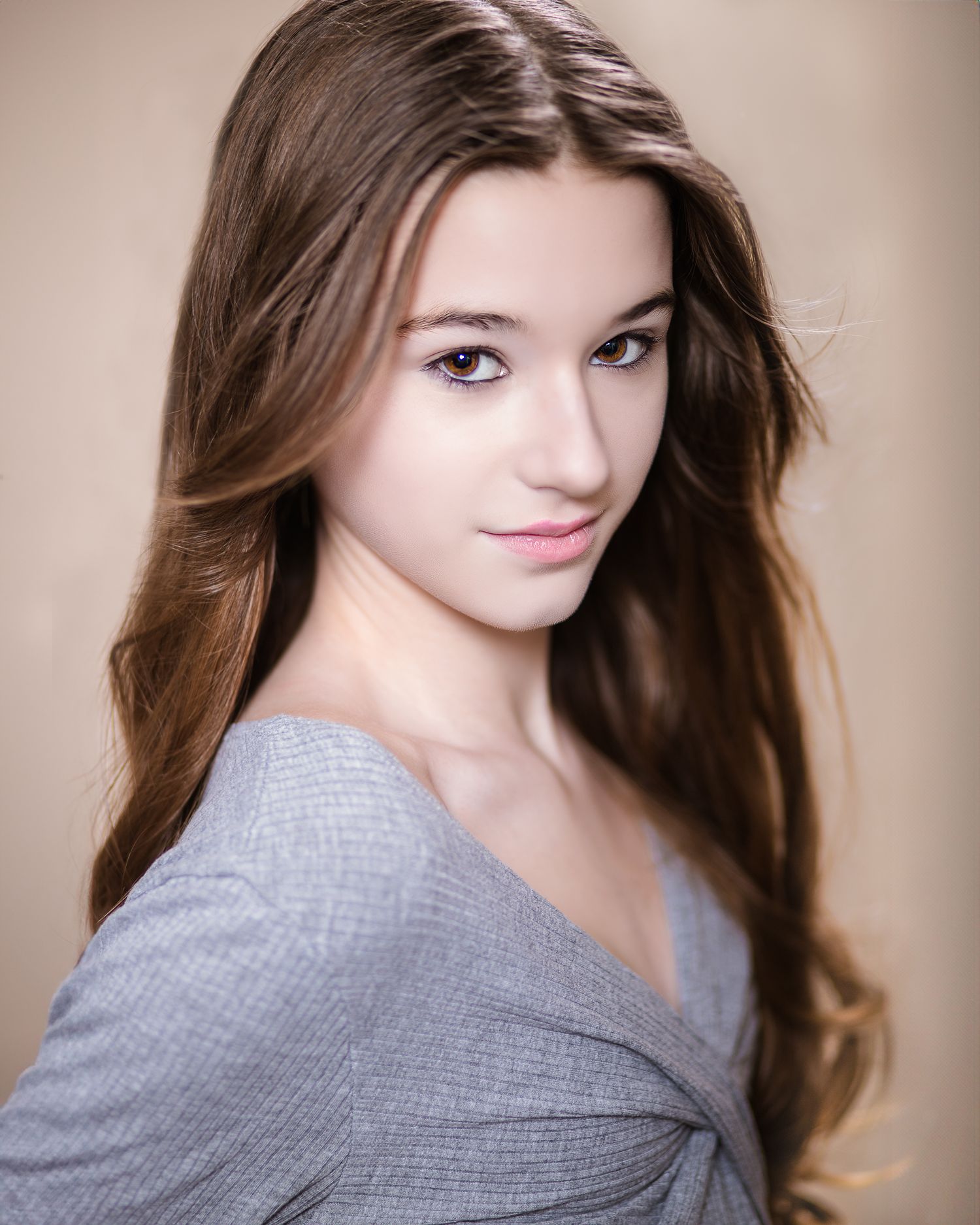 Studio portrait showing long brown hair and soft lighting against neutral background.