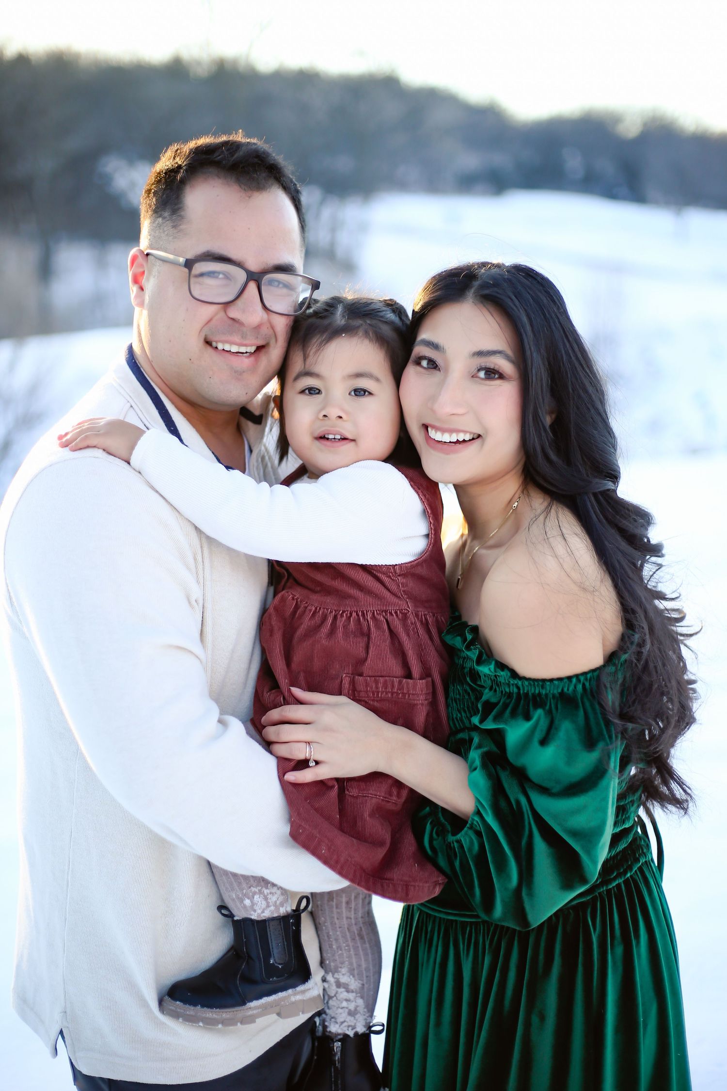 Family poses together outdoors in manhattan KS  winter wearing festive holiday attire with snow in background.