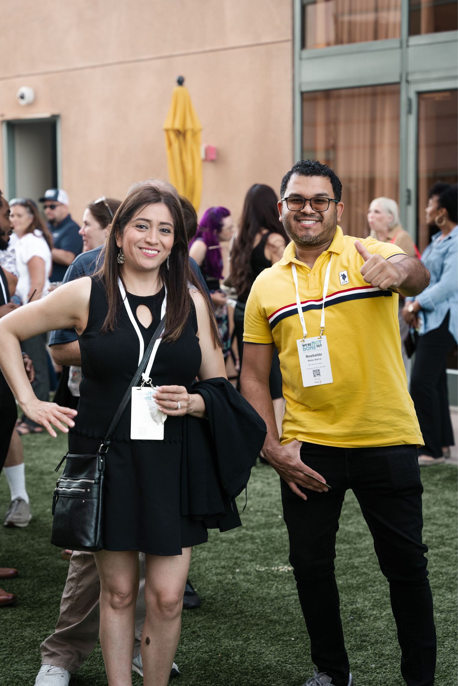 Group of attendees socializing and networking on grass lawn at outdoor conference or event.