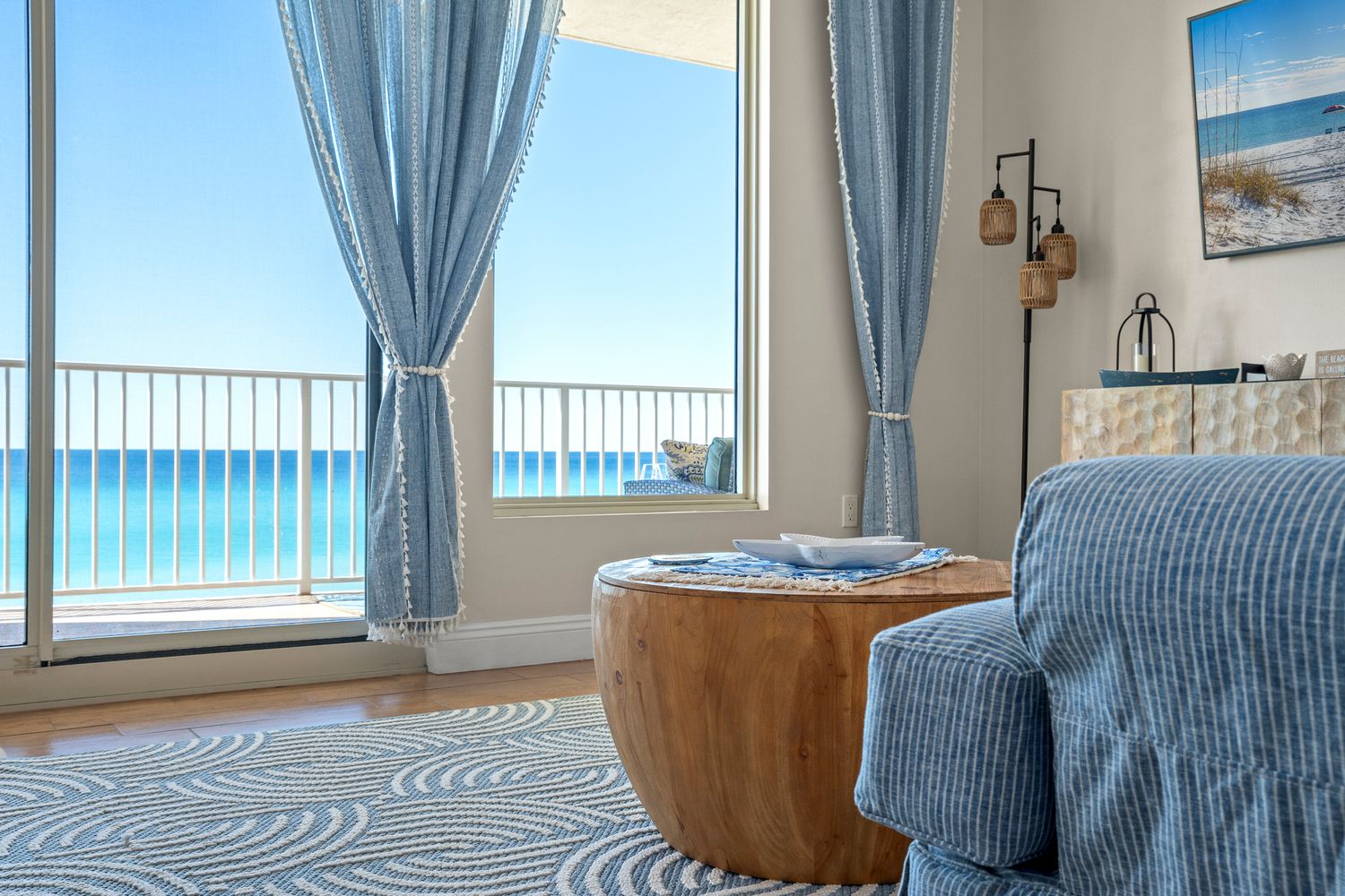 Coastal bedroom with blue curtains features panoramic ocean views and modern beach-inspired decor.