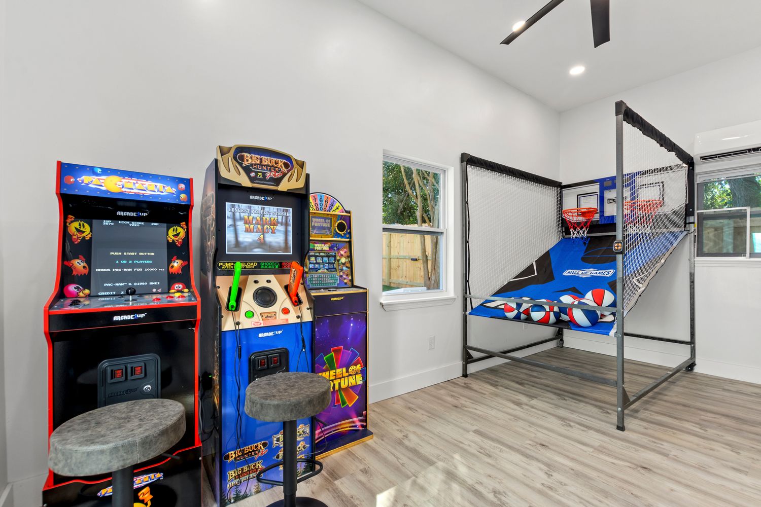 Game room featuring arcade cabinets, pinball machines and basketball arcade game with modern wood flooring and lighting.