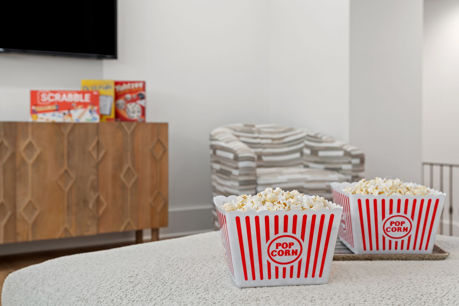 Classic red and white striped popcorn containers sit on a counter with snacks and storage cabinet in background.