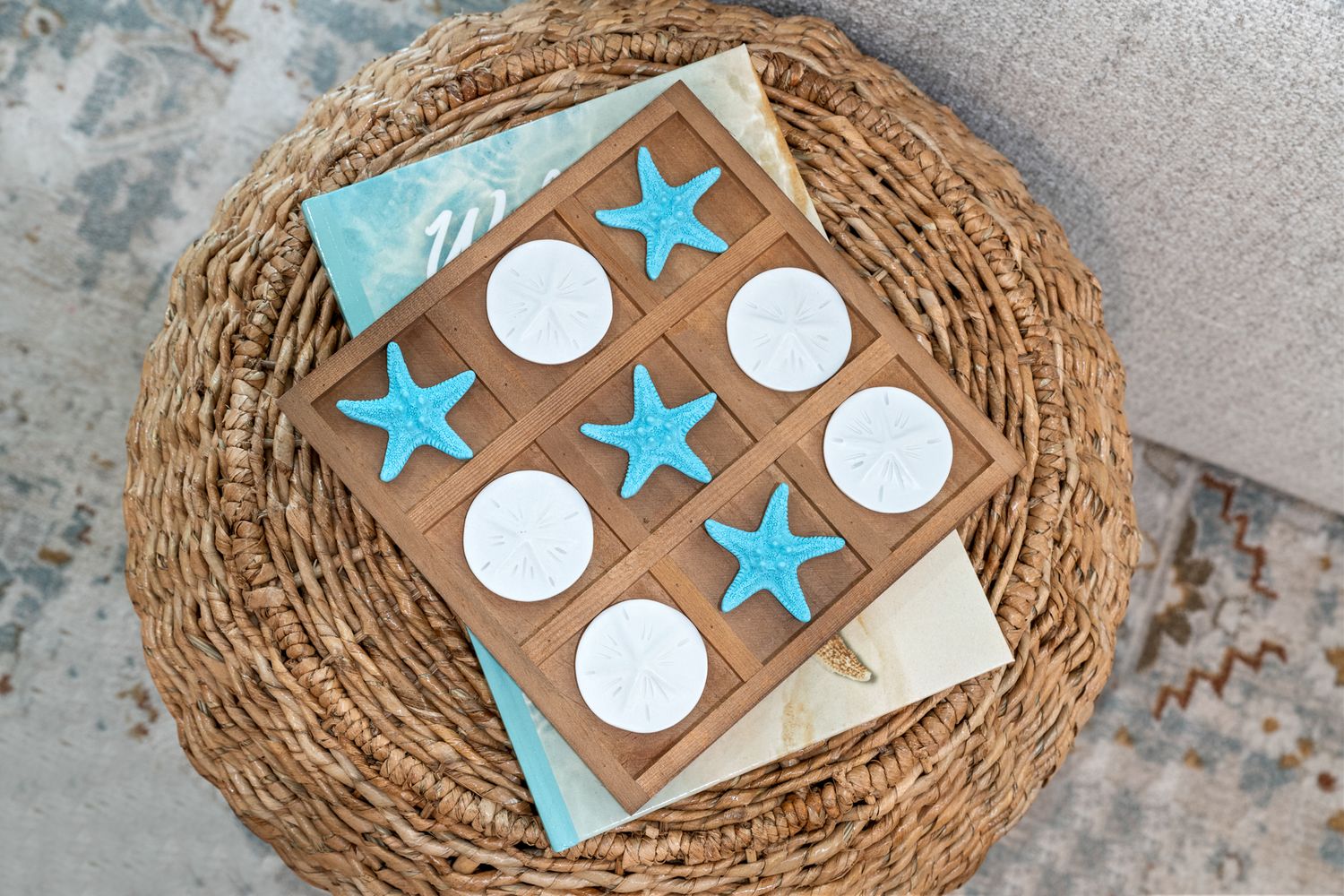 A wicker basket containing a wooden tic-tac-toe board with white circles and blue stars as game pieces.