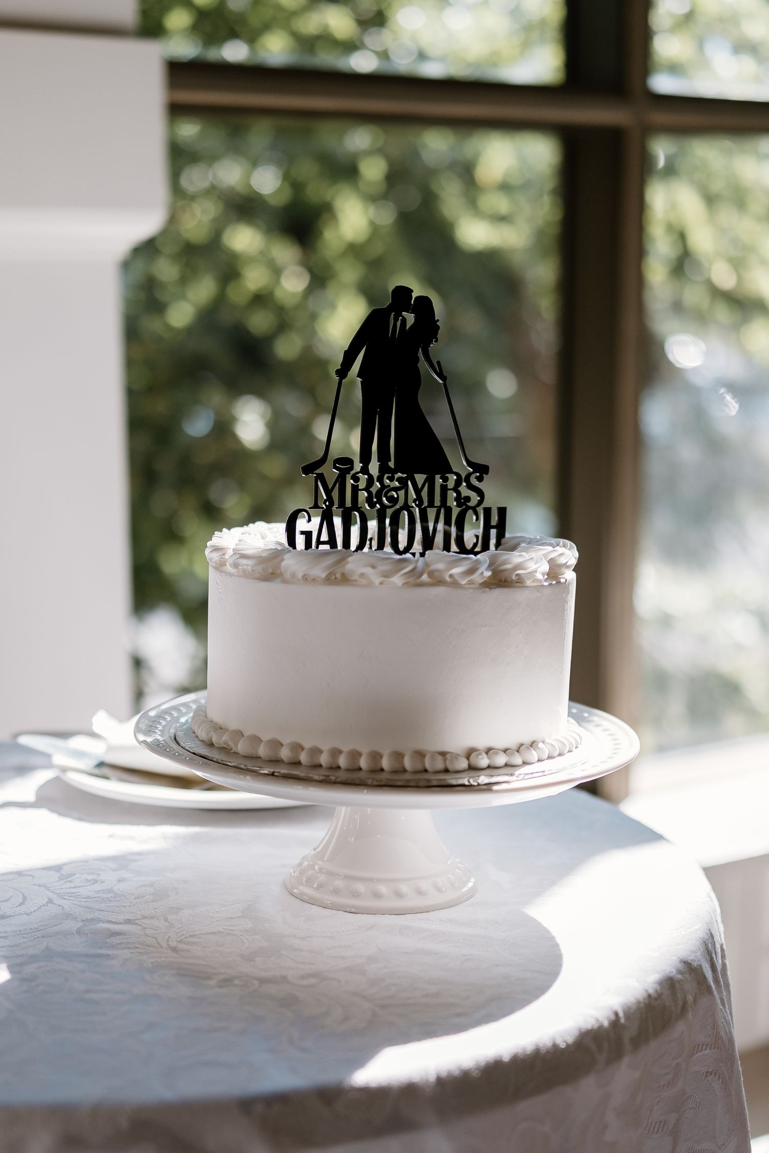 White wedding cakes displayed with silhouette cake toppers on an elegant table setting.