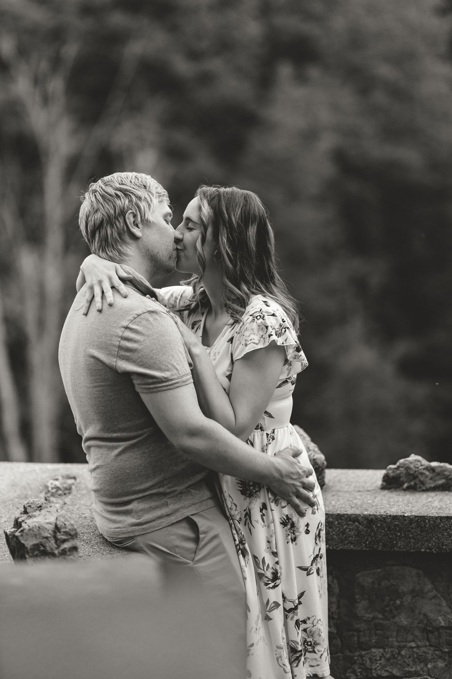 An intimate black and white portrait of a couple sharing a tender moment outdoors.