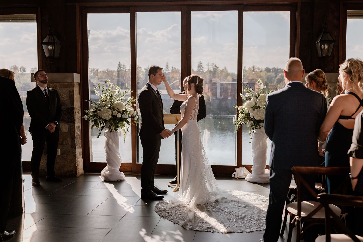 Wide shot of indoor wedding ceremony with guests watching the exchange of vows.