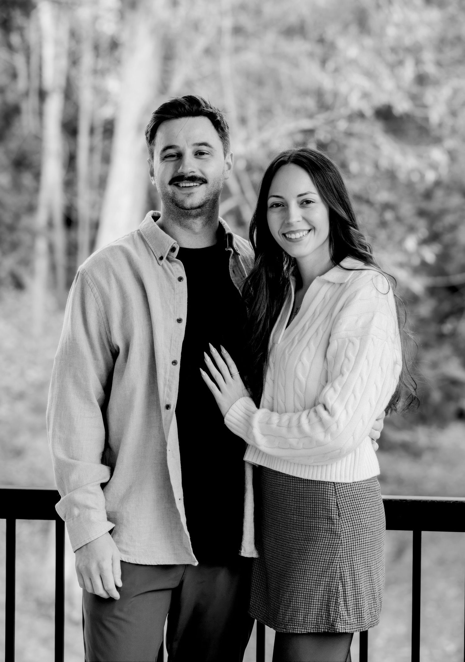 A couple poses together in casual autumn outfits against a natural backdrop.